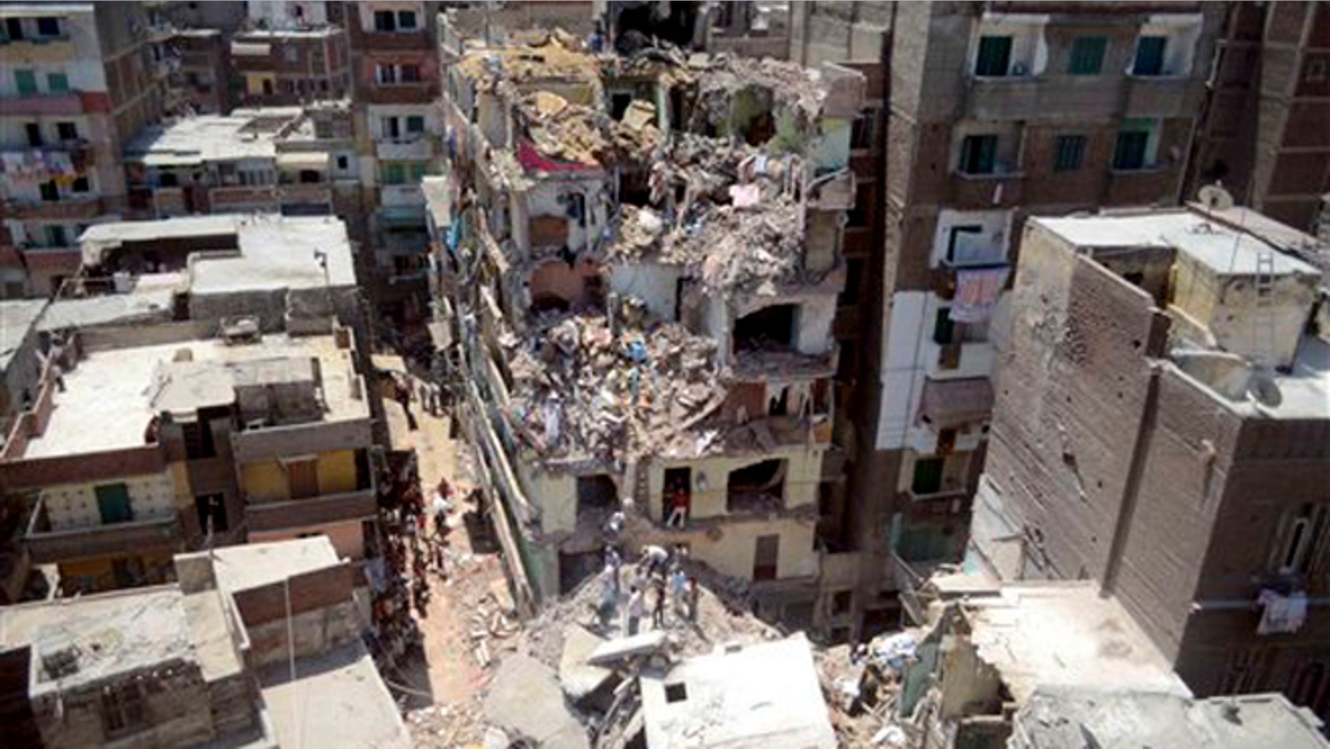 July 15, 2012: In this file photograph, rescue workers look for survivors buried under debris of damaged buildings following the collapse of an 11-story building under construction onto three adjacent buildings that killed at least 10 people in the Gomrouk neighborhood of Alexandria, Egypt.