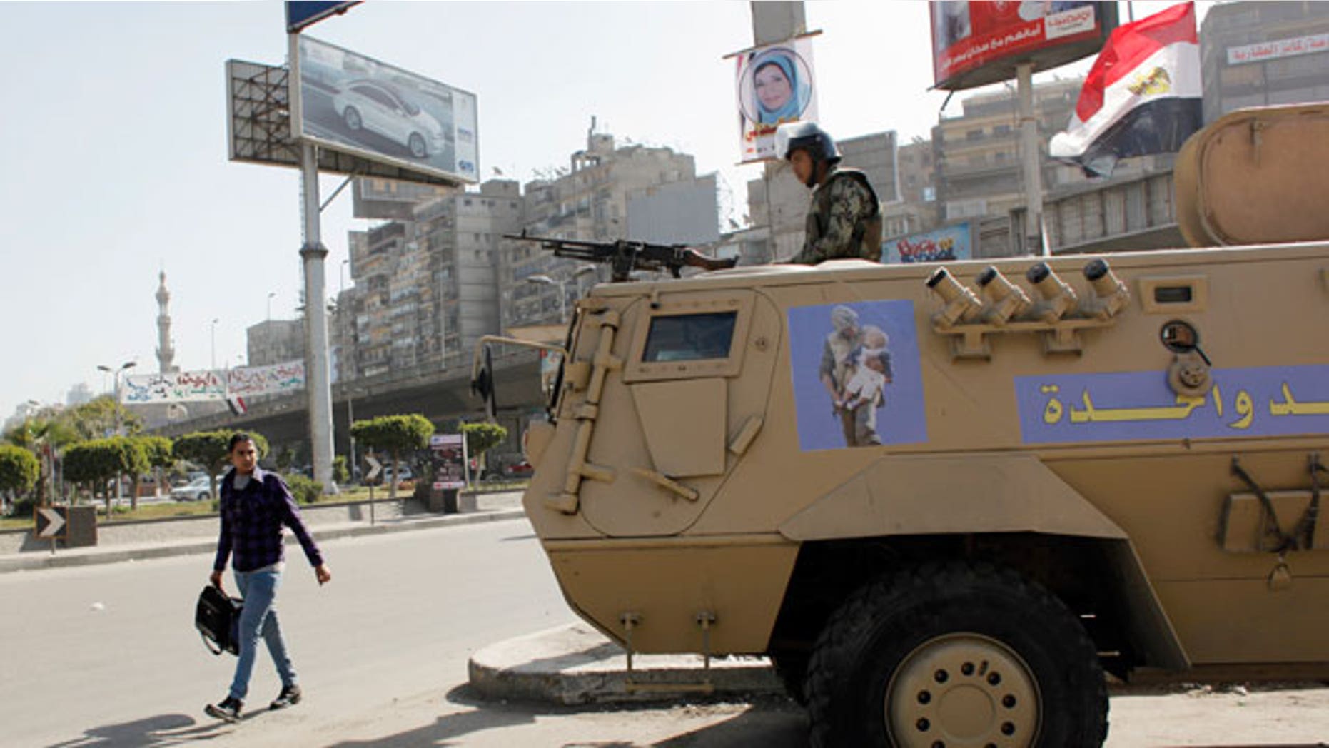 Feb. 11, 2012: An Egyptian man passes by an army patrol with a soldier on top of an armored vehicle flying the national flag and a sticker on the body with Arabic that reads "the army and the people are one hand," during a general strike in Cairo, Egypt.