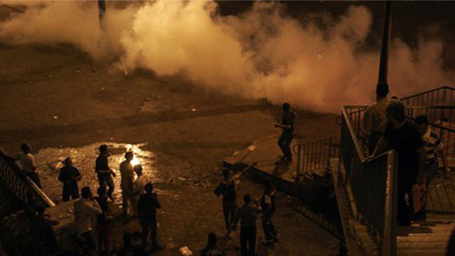 Smoke from tear gas fills the street as protesters clash with Egyptian security forces in Cairo Egypt, Sunday, Oct. 9, 2011.