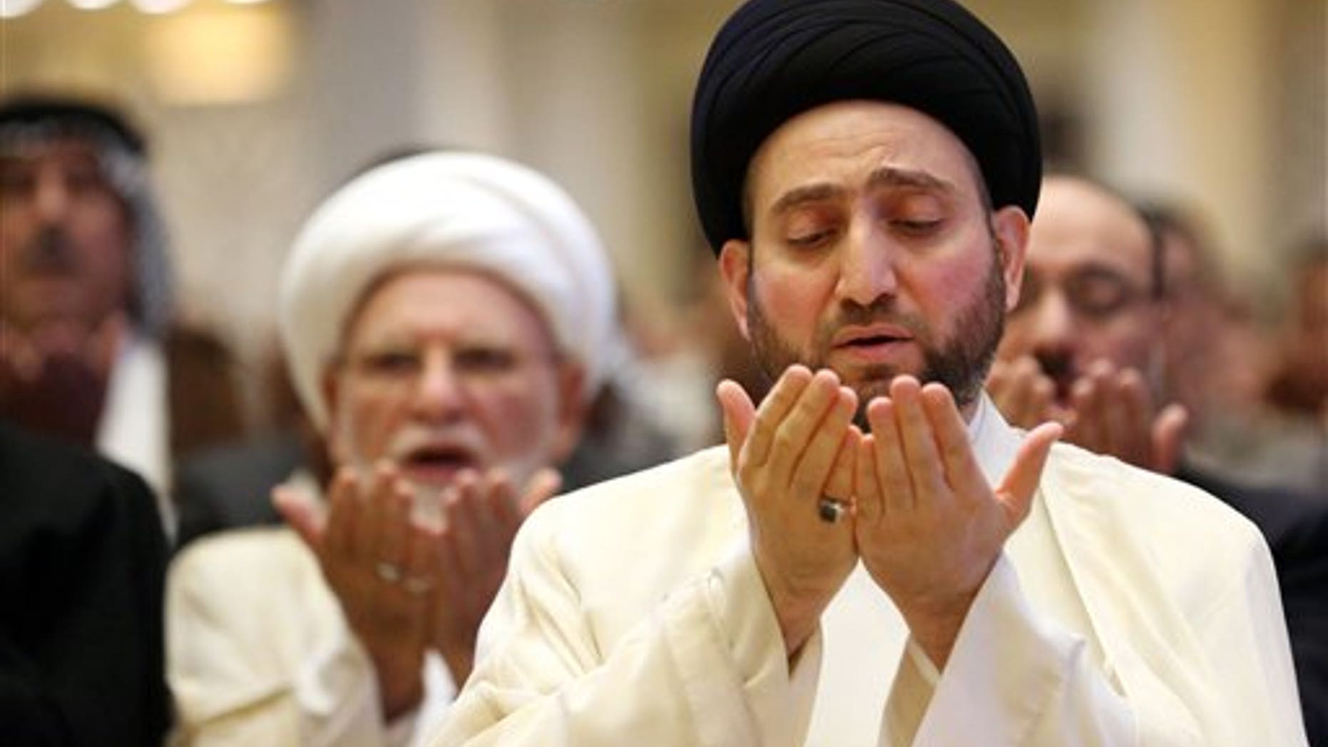 Ammar al-Hakim, right, the leader of the Supreme Islamic Council of Iraq, take part in the Eid al-Fitr prayer in Baghdad, Iraq, Tuesday, July 29, 2014. The Eid al-Fitr holiday marks the end of the holy fasting month of Ramadan. (AP Photo/Hadi Mizban)