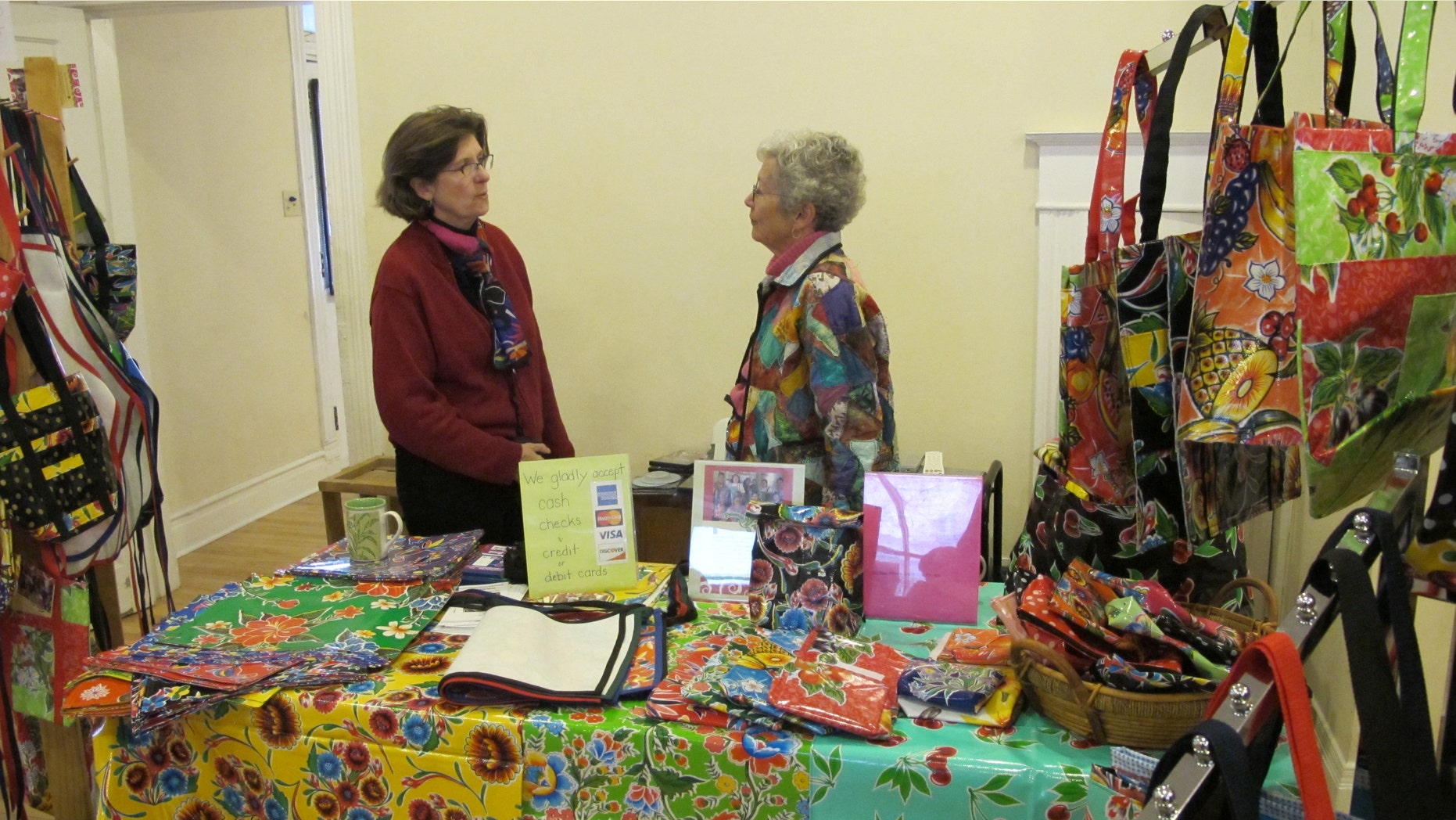Polly Edmunds from Border Partners speaks with a fellow seller. Edmunds sells waterproof items made from Mexican oilcloth to benefit Palomas Oilcloth Designs.