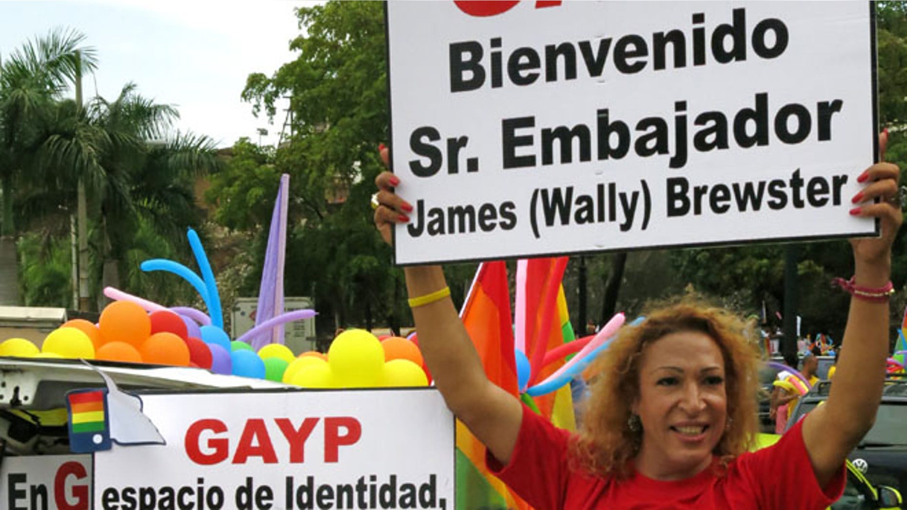 FILE - In this June 30, 2013 file photo, people welcome U.S. Ambassador James "Wally" Brewster during a gay pride parade in Santo Domingo, Dominican Republic. The signs read in Spanish "Welcome Mr. Ambassador James "Wally" Brewster," right, and "Identity space, equality zone." Activists say Brewster's presence has helped a cultural shift that has allowed gay Dominicans to run for office openly as homosexuals. âWally has become an iconic figure in the LGBT movement because the movement does have strong local figures,â said prominent activist Alexander Mundary. (AP Photo/Ezequiel Abiu Lopez, File)