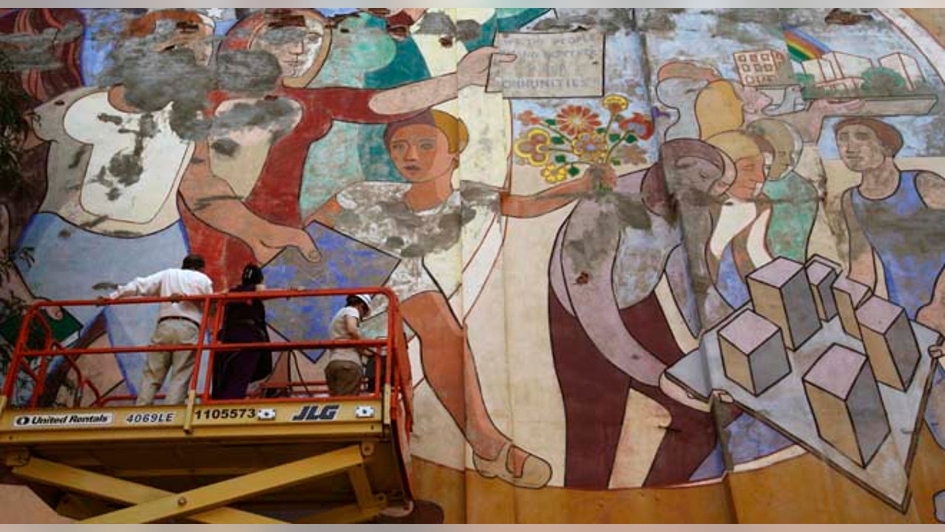 In this Sept. 13, 2011 photo, a member of the media, the widow of the artist and an art conservator survey damage to Arnold Belkin's 1972 mural "Against Domestic Colonialism," which adorns a playground wall in the Hell's Kitchen neighborhood of Manhattan, in New York. The national organization Heritage Preservation says Belkin's mural is one of the most endangered public murals in the country and the group, as well as members of the community, are looking into ways to preserve it. (AP Photo/Kathy Willens)