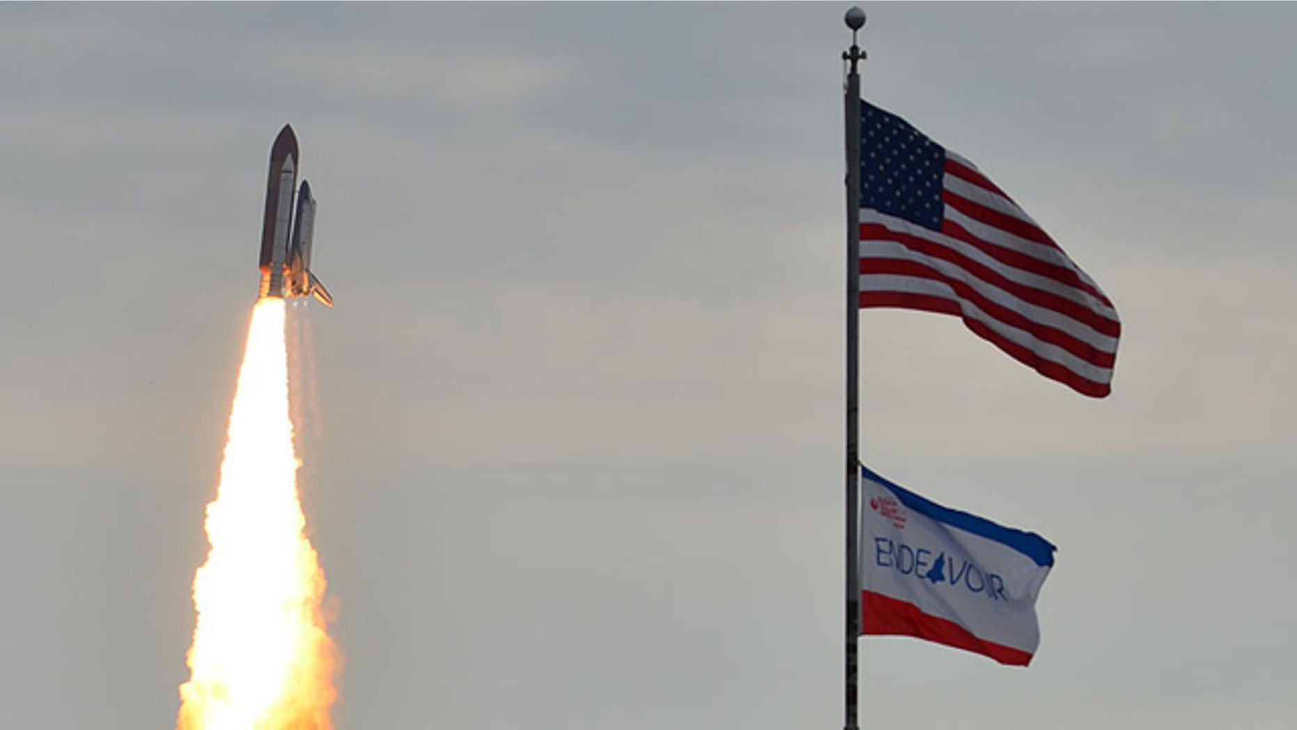 Space shuttle Endeavour appears to fly past flags in the foreground, on its way to the International Space Station. Launch of the STS-134 mission took place at 8:56 a.m. EDT on May 16.