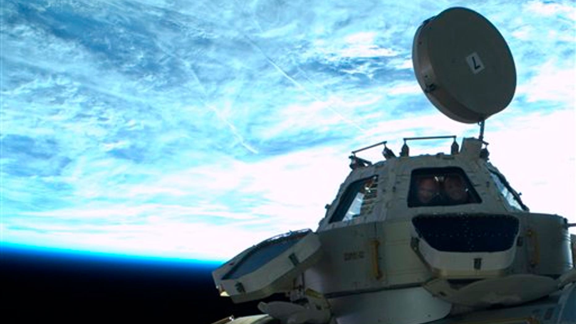 May 26: In this image provided by NASA astronauts Mike Kelly, left, and Ron Garan get their picture taken in the cupola window by astronaut Mike Fincke while he floats outside the International Space Station during the third spacewalk. (AP/NASA)