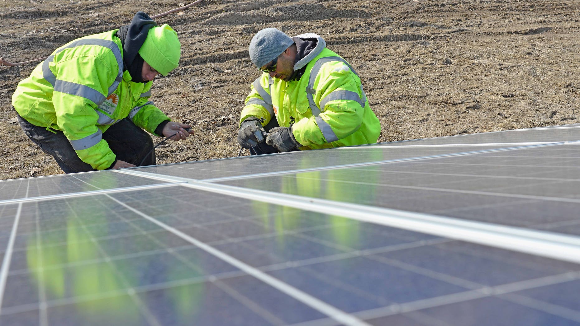 CLEVELAND, OH - MARCH 25: (L-R) Orlando Santaella Jr. and Orlando Santaella Sr. of Evergreen Energy Solutions work on a ground-mounted solar array located on Euclid Ave across the street from Lakeview Cemetery on March 25, 2014 in Cleveland, Ohio. (Photo by Duane Prokop/Getty Images for TakePart.org)
