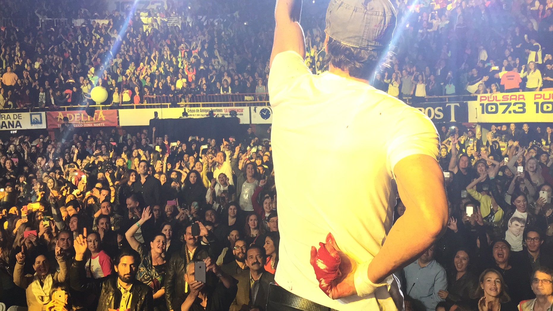 May 30, 2015. Enrique Iglesias holds his bloodied hand behind his back during a concert in Tijuana, Mexico.