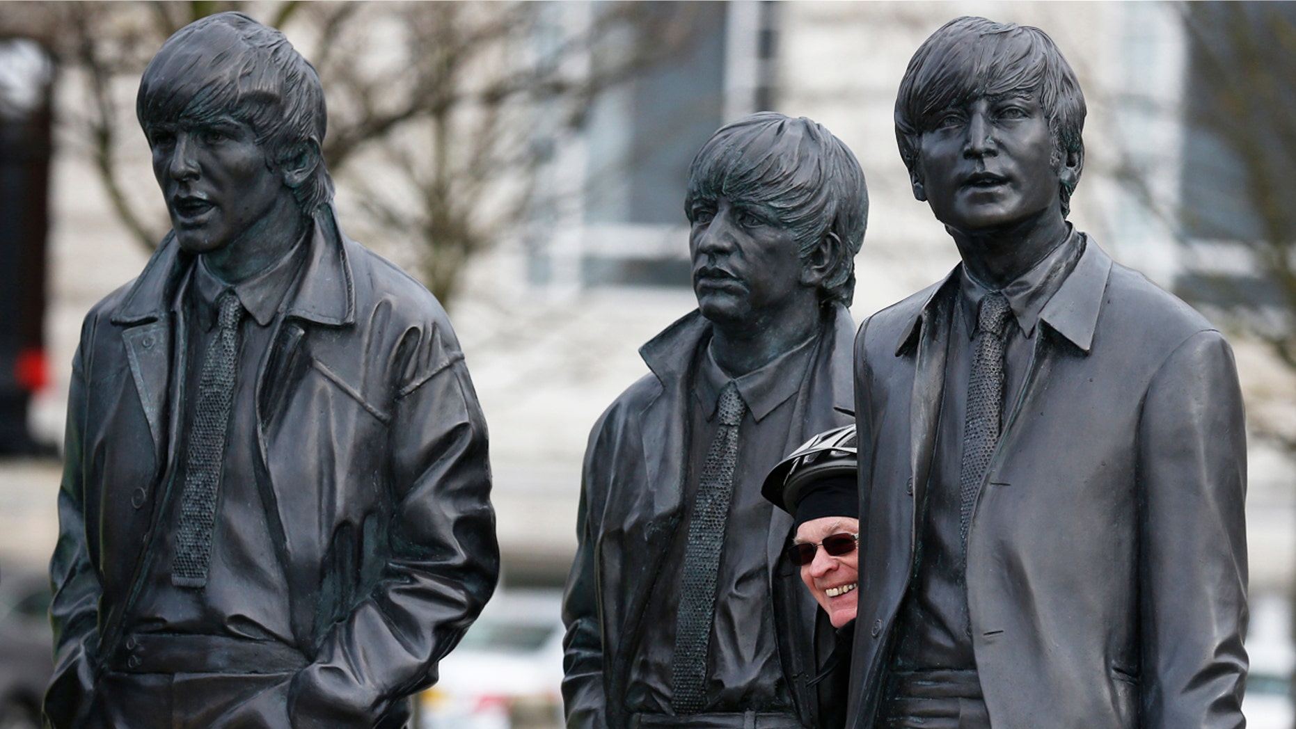 A fan poses next to a statue of The Beatles at the Pier Head in Liverpool, Britain March 9, 2016.