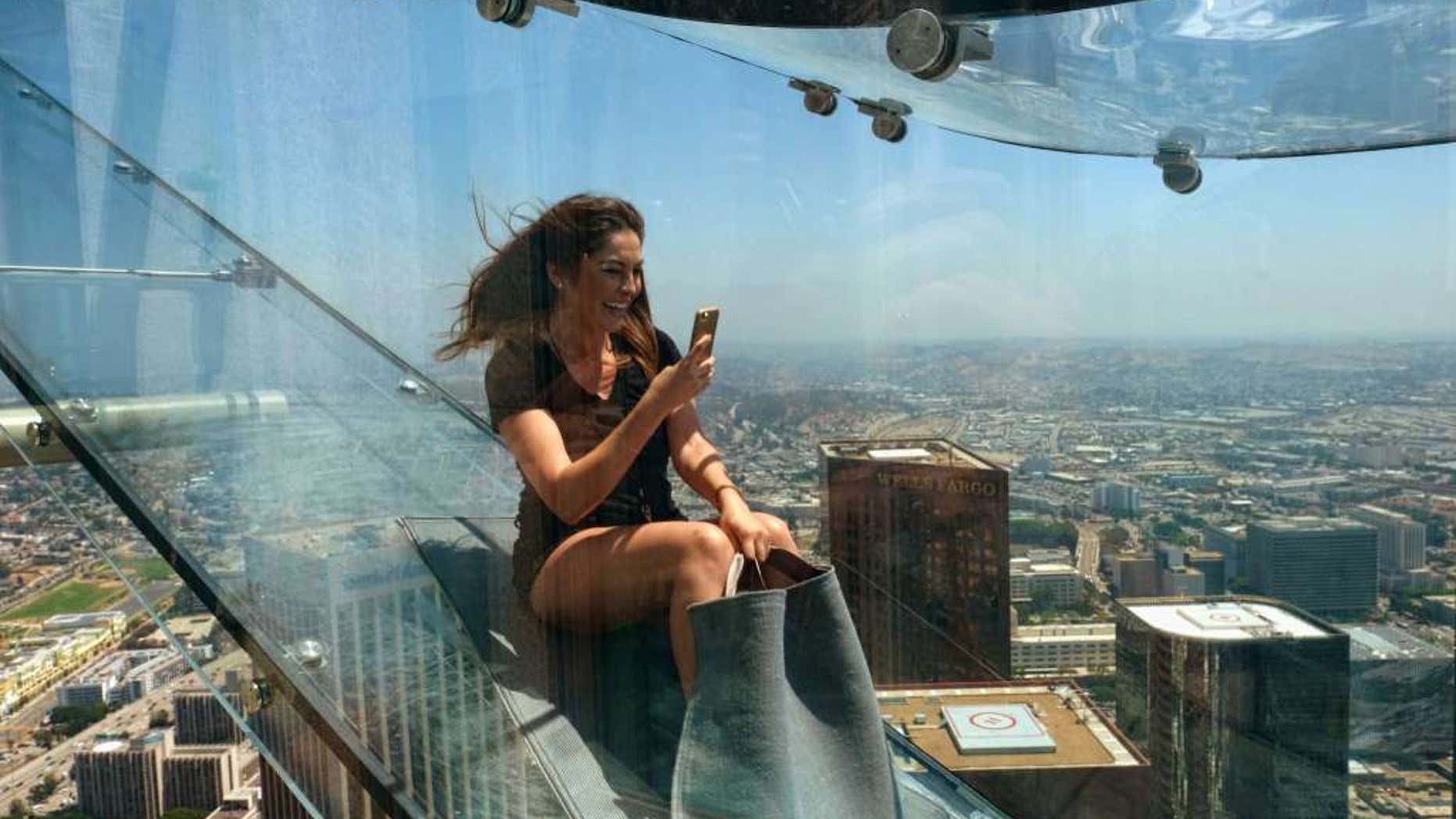 Angela Cox a reporter with Seven Network Australia takes a photo with her phone as she takes ride down the U.S. Bank Tower building's 1,000 foot tall "Skyslide" in downtown Los Angeles on Thursday, June 23, 2016.