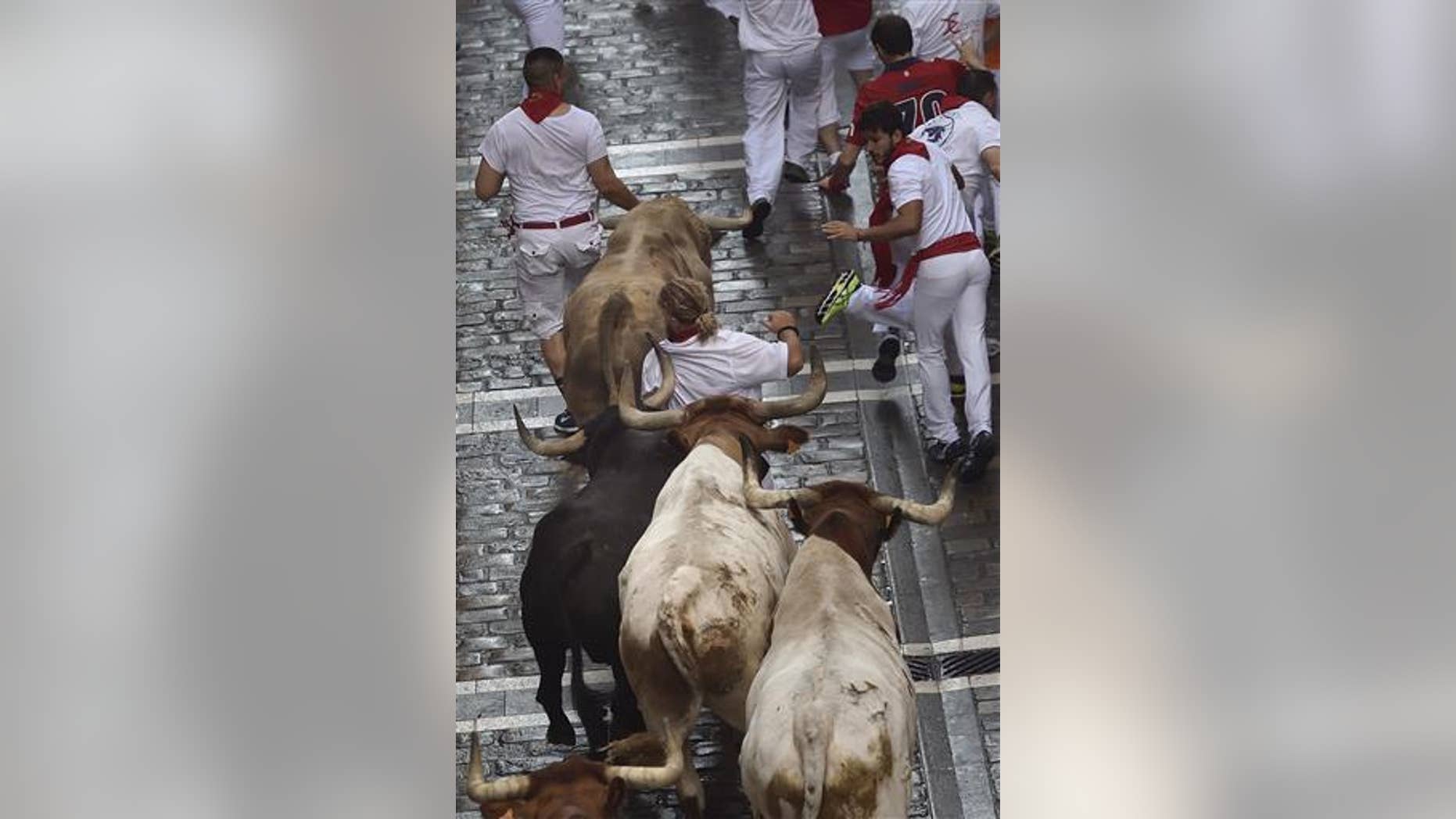 A runner runs in front Fuente Ymbro fighting bulls on the Estafeta street during the first running of the bulls at the San Fermin Festival, in Pamplona, Spain.