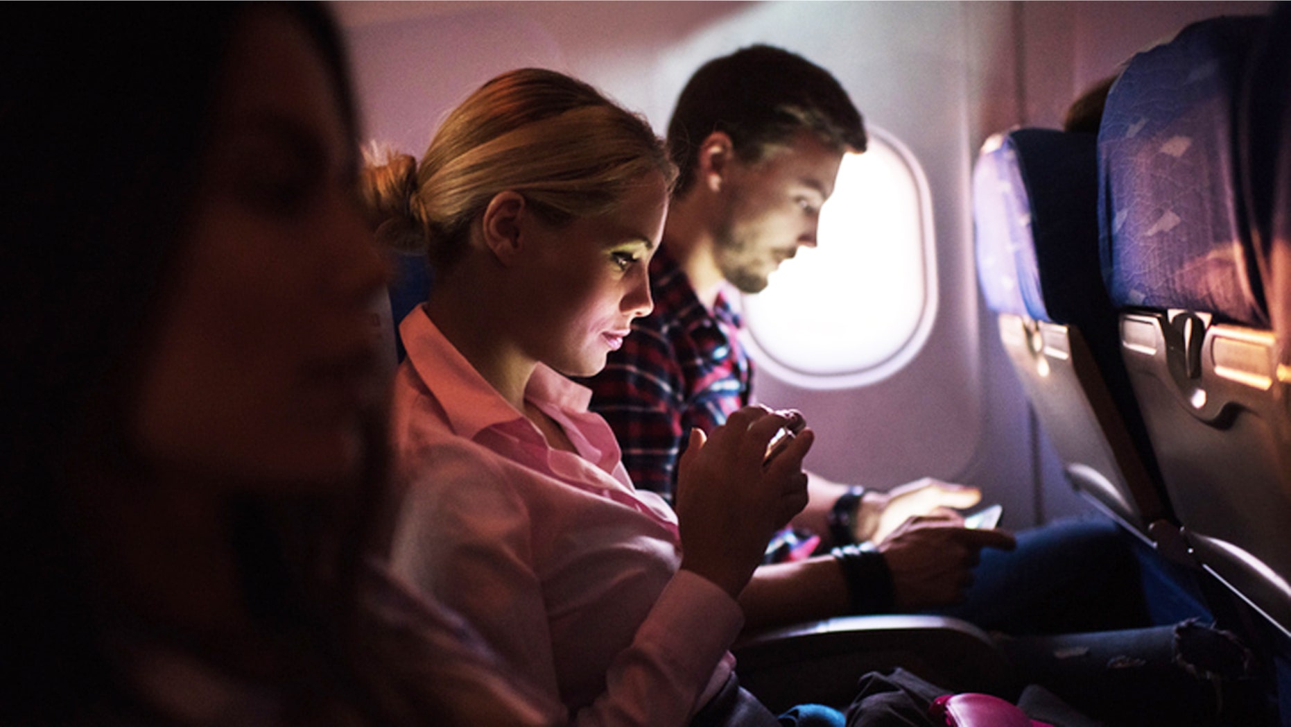 People traveling by airplane. Focus is on young woman text messaging.
