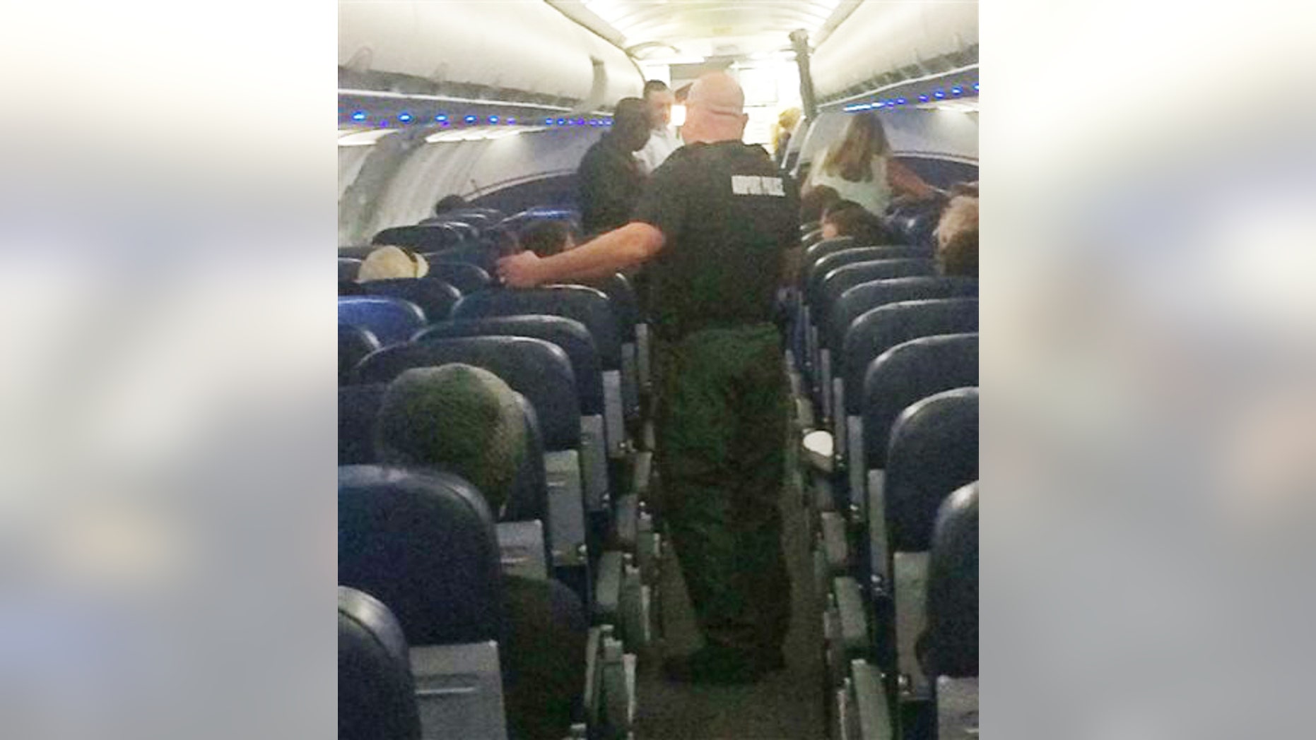 This Tuesday, Nov. 3, 2015, photo provided shows airport police aboard a plane after an emergency landing at Eisenhower National Airport in Wichita, Kan. The U.S. Attorney's Office says a disruptive passenger who forced the diversion of the American Airlines flight from Phoenix to New York will face federal charges.