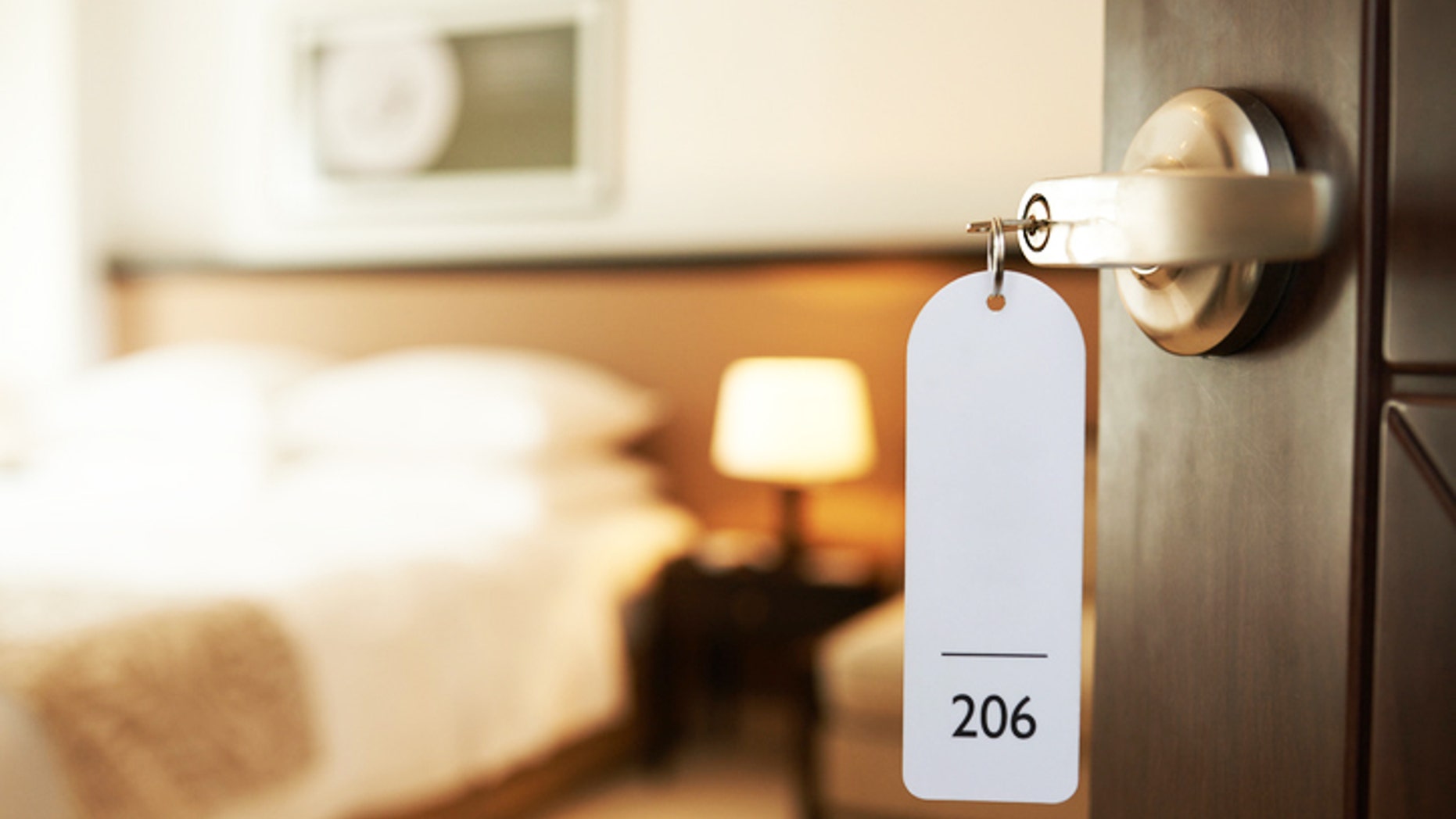 Opened door of hotel room with key in the lock