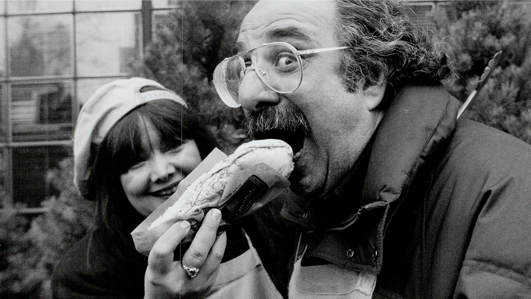 Actor Harvey Atkin tucks into hot dogs, as City-TV's Brona Brown looks on, during a celebrity outdoor barbecue to raise money for Variety Village.