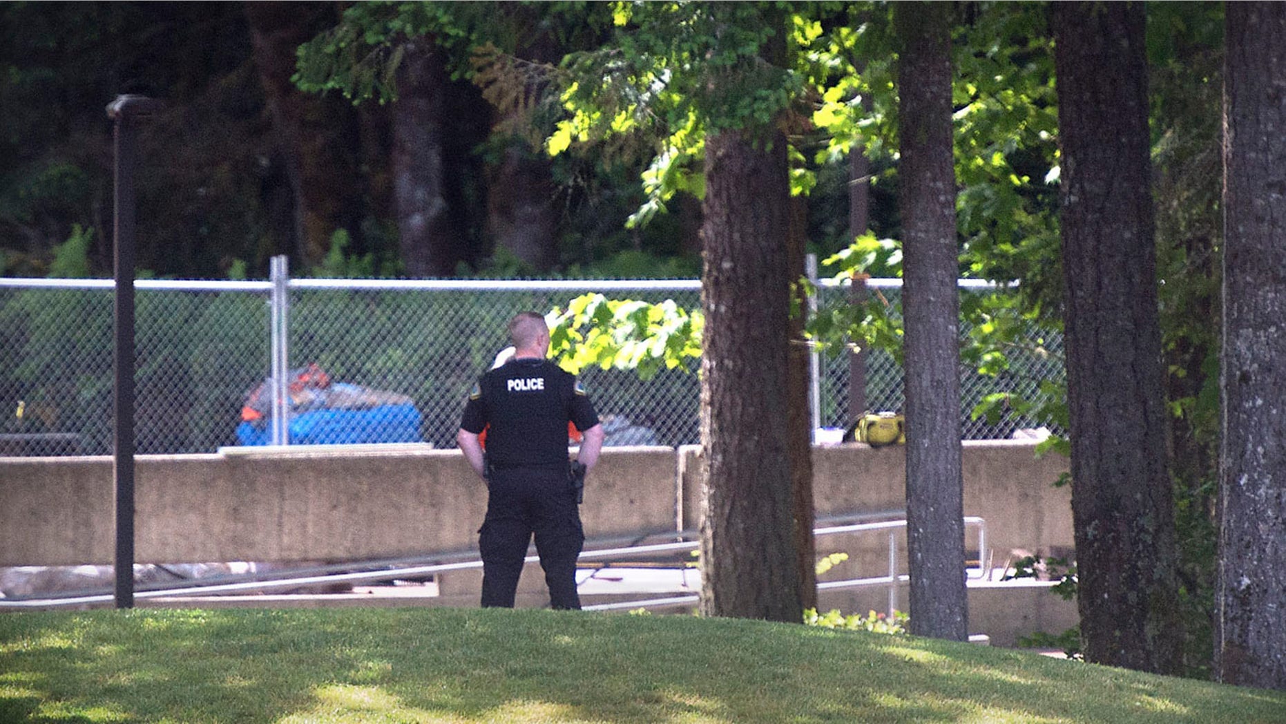 An Evergreen State College police officers keeps watch over campus as student evacuate following a "direct threat" on Thursday, June 1, 2017. The announcement posted on the school's website Thursday asked everyone to leave the Olympia campus or return to residence halls for further instructions. The post did not provide other details. (Tony Overman /The Olympian via AP)