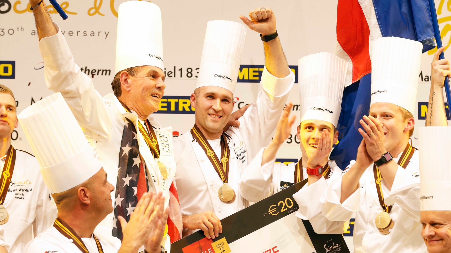 Mathew Peters of Team USA, center, celebrates on the podium with teammates after winning the "Bocuse d'Or" (Golden Bocuse) trophy, in Lyon, central France, Wednesday, Jan. 25, 2017. The contest, known as the Olympics of the food world, was started in 1987 by Lyon chef Paul Bocuse to reward young international culinary talents.