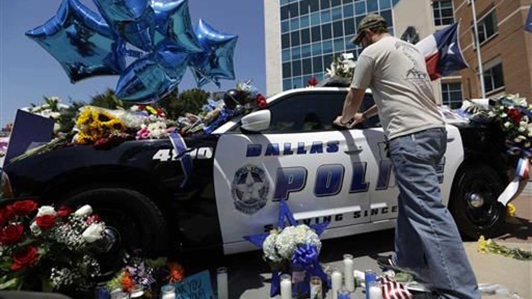 Michael O'Mahoney, a former police officer, places his patch on a make-shift memorial outside the Dallas police headquarters.