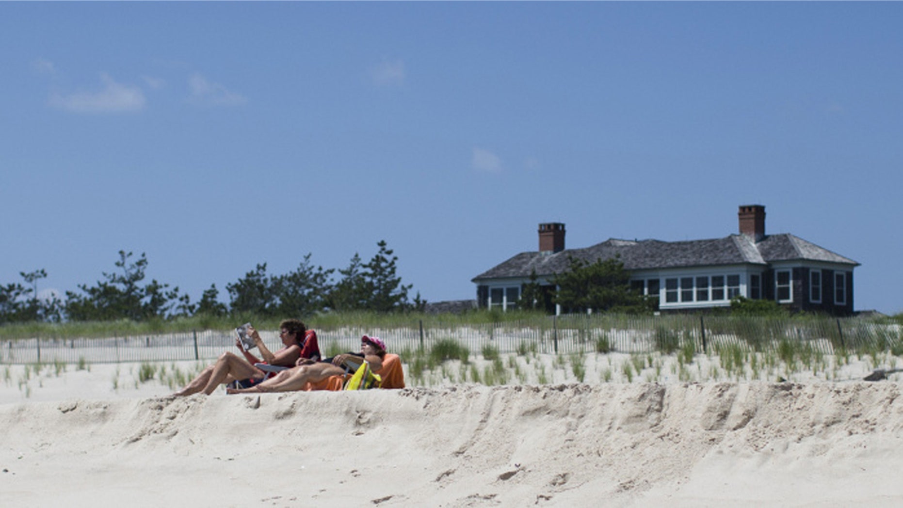 Beachgoers relax near a beachfront property in Southampton, N.Y.
