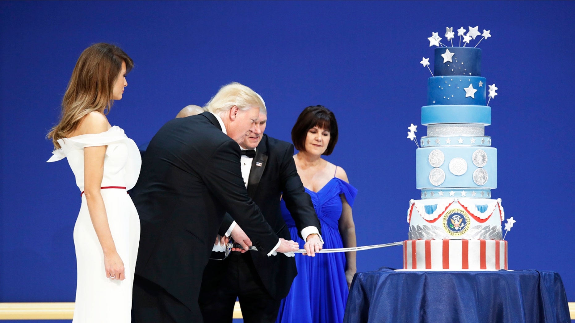 First lady Melania Trump watches as President Donald J. Trump, and Vice President Mike Pence, right,are helped by Coast Guard Petty Officer 2nd Class Matthew Babot, center, as they cut a cake at The Salute To Our Armed Services Inaugural Ball Friday, Jan. 20, 2017, in Washington. Karen Pence watches at right. (AP Photo/Alex Brandon)