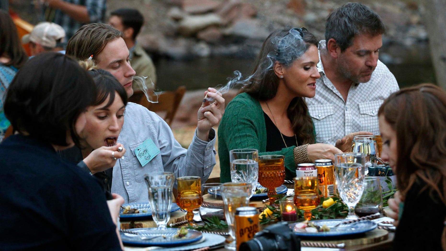 Diners smoke marijuana as they eat dishes prepared by chefs during an evening of pairings of fine food and craft marijuana strains served to invited guests dining at Planet Bluegrass, an outdoor venue in Lyons, Colo.