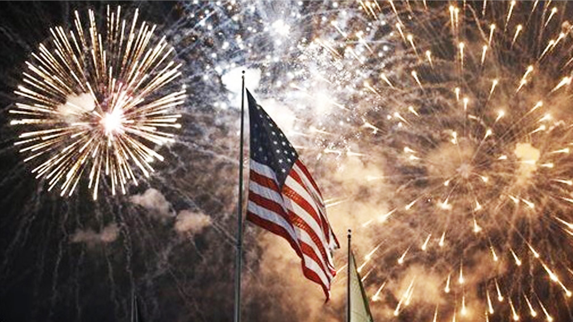 Fireworks explode behind a United States flag during a Fourth of July celebration at State Fair Meadowlands, East Rutherford, N.J.