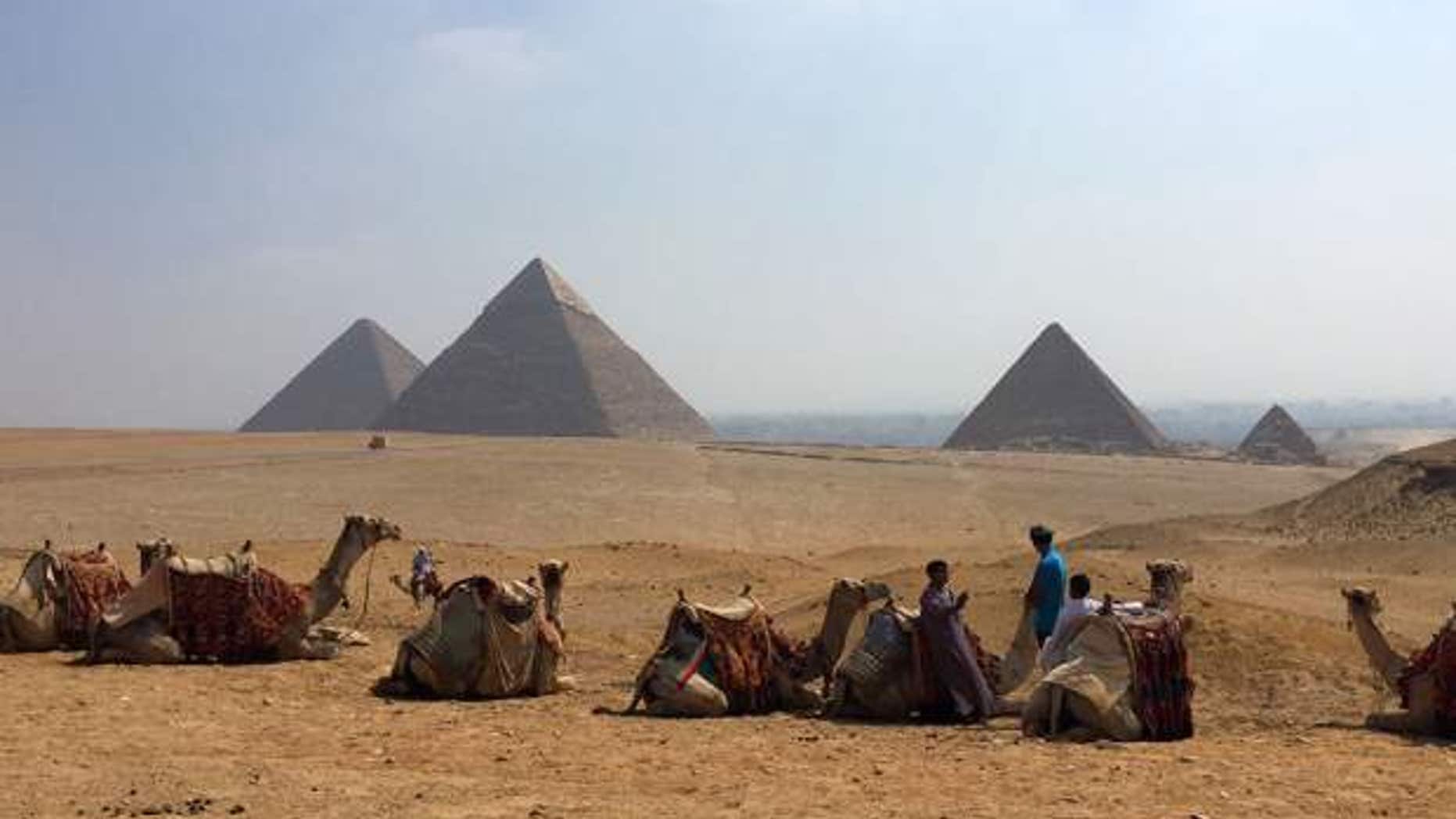 Camels rest between rides with their owners against the backdrop of the pyramids in Giza, Egypt. With Egypt’s once-thriving tourism industry in decline, visitors face smaller crowds-- but eager tour guides and pushier souvenir vendors.