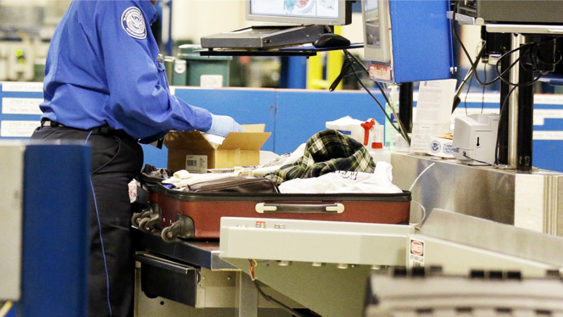 A TSA agent inspects a package inside a suitcase.