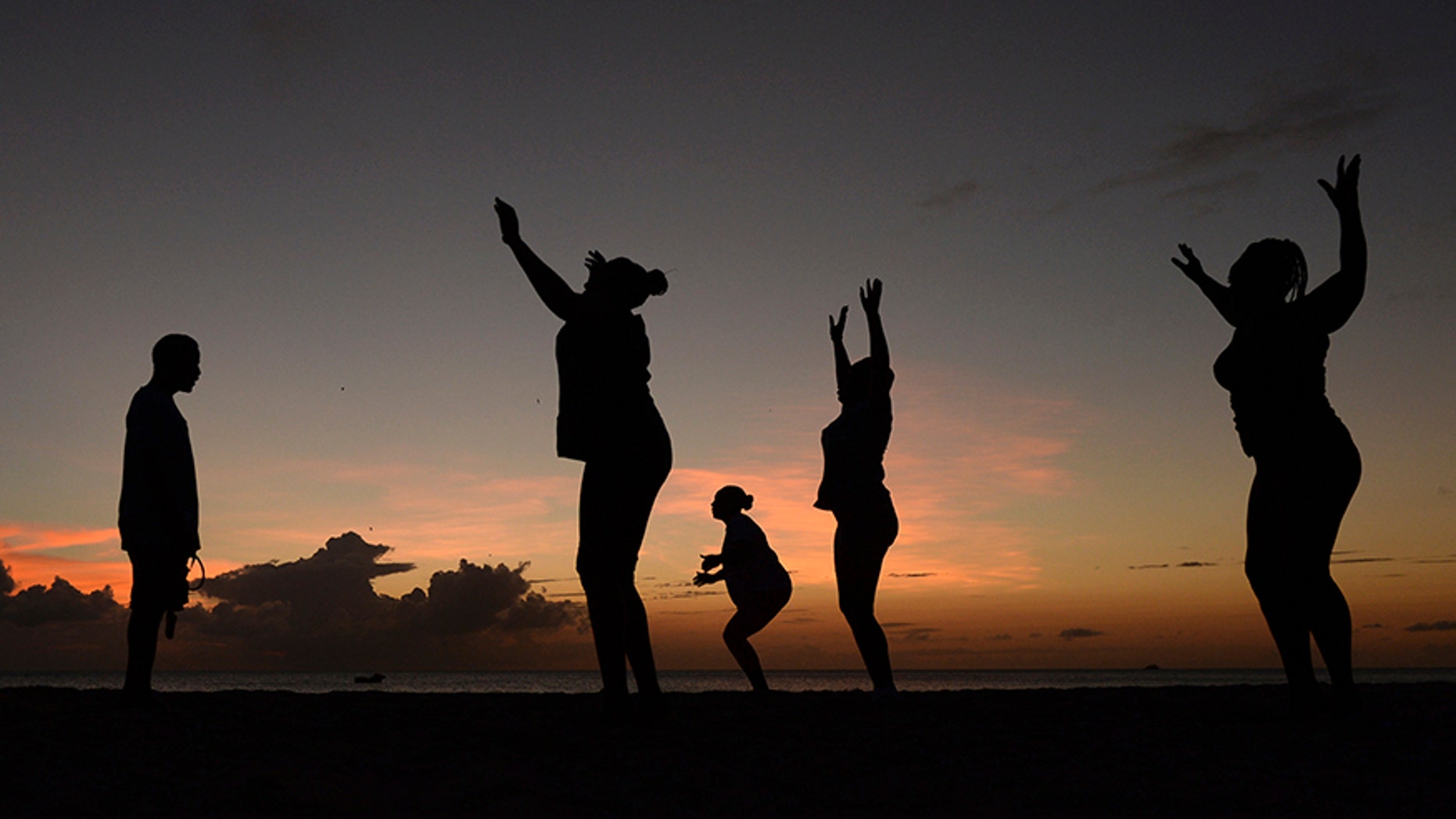 Women exercise in front of a trainer as the sun sets, March 13, 2014.
