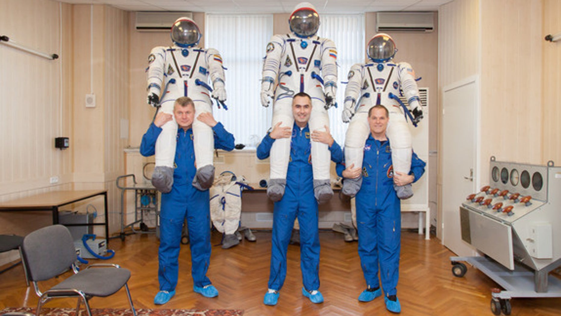 At the Baikonur Cosmodrome in Kazakhstan, the Expedition 33 crew share a playful moment Oct. 10, 2012 during the first of two so-called “fit check” dress rehearsal sessions. From left to right are Soyuz Commander Oleg Novitskiy, Flight Engineer