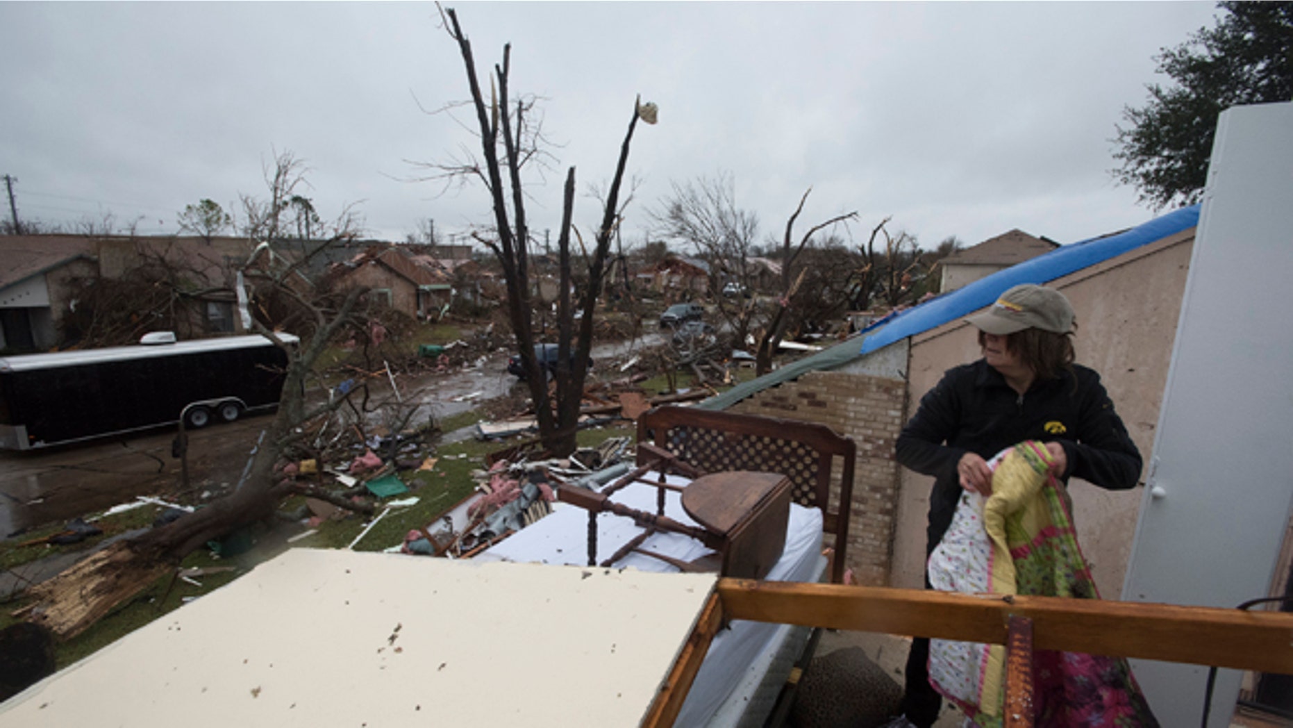 Delores Downard salvages items from her son's house in Rowlett, Texas, Sunday, Dec. 27, 2015, the morning after it was struck by a tornado. At least 11 people died and dozens were injured in apparently strong tornadoes that swept through the Dallas area and caused substantial damage this weekend. (AP Photo/Rex C. Curry)