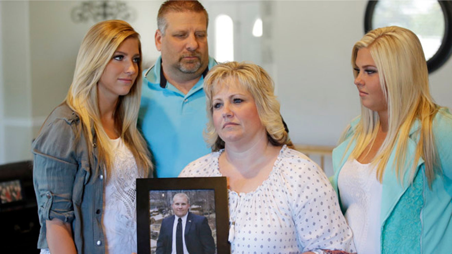 Laurie Holt holds a photograph of her son Josh while daughters Jenna, left, Katie, right, and husband Jason look on.