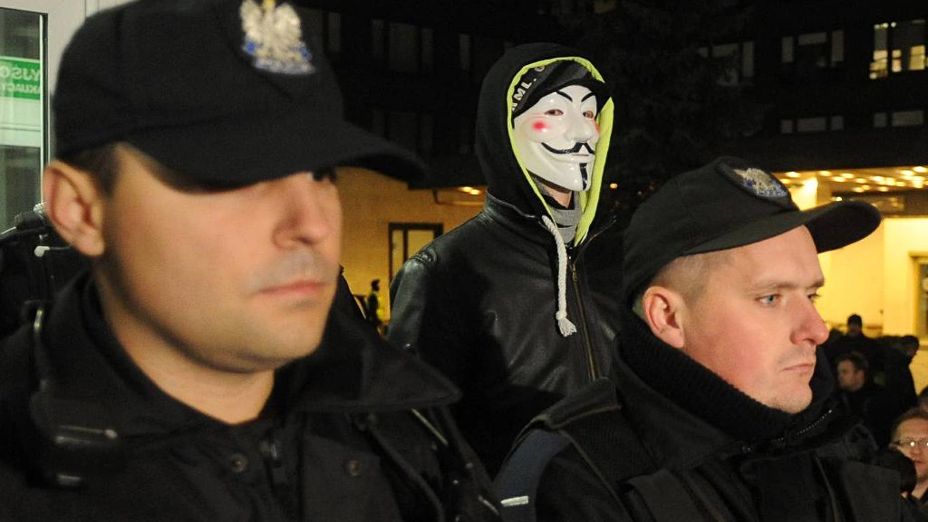 Police officers block the entrance to the National Electoral Office as a man wearing a mask stands behind, in Warsaw, Poland, Thursday, Nov. 20, 2014. Earlier a group of right wing activists entered the building and began to occupy it demanding the members of the National Electoral Office to resign. Prosecutors are investigating a hacking attack on the website of Poland's voting commission, while a top official has resigned over irregularities that are delaying the vote count in recent local elections. (AP Photo/Alik Keplicz)