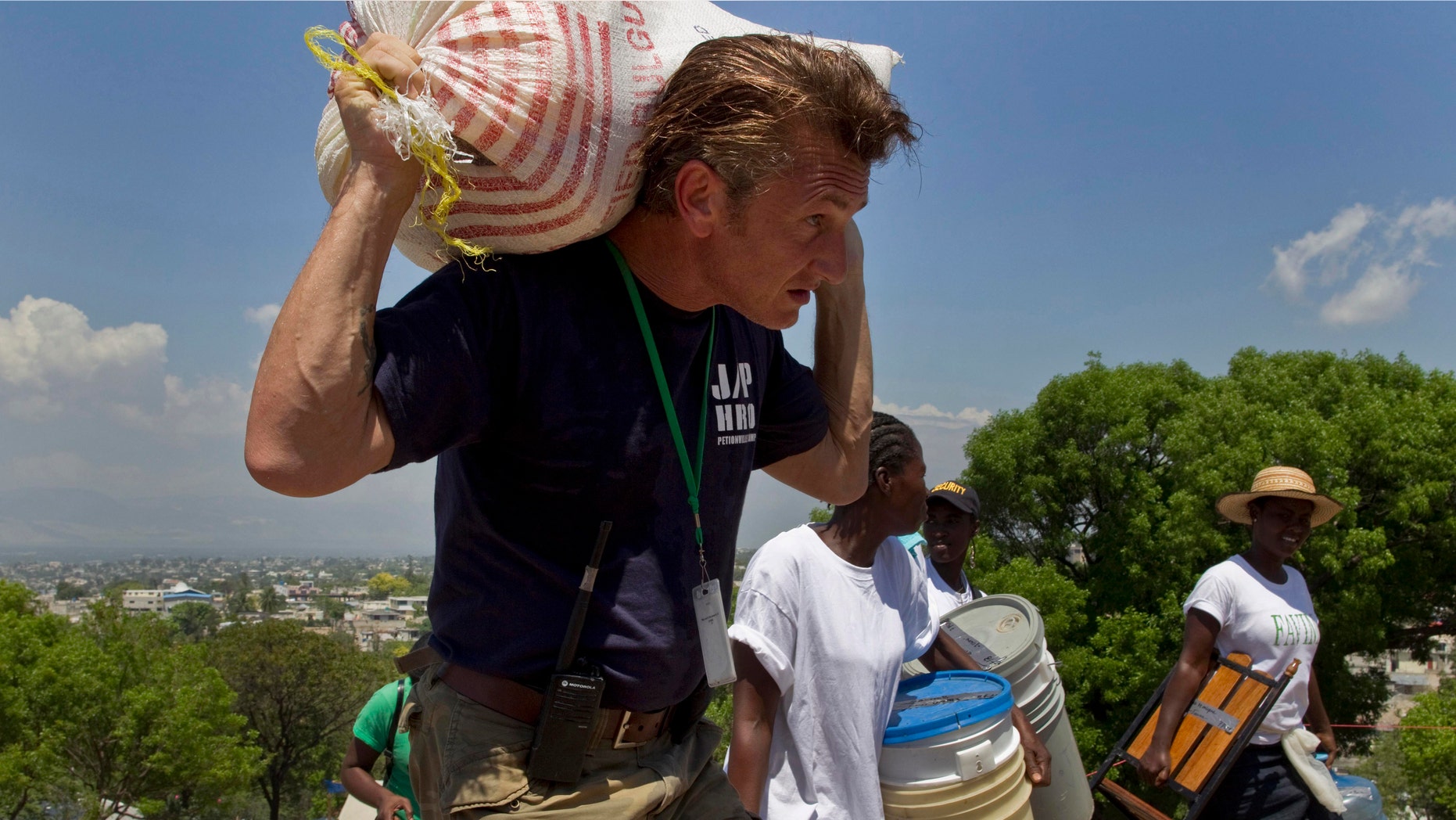 In this Saturday, April 10, 2010 file photo, U.S. actor Sean Penn carries the belongings of a person displaced by the earthquake as people are relocated from the Petionville Golf Club to a new camp, Corail-Cesselesse, in Port-au-Prince, Haiti. (AP Photo/Ramon Espinosa)