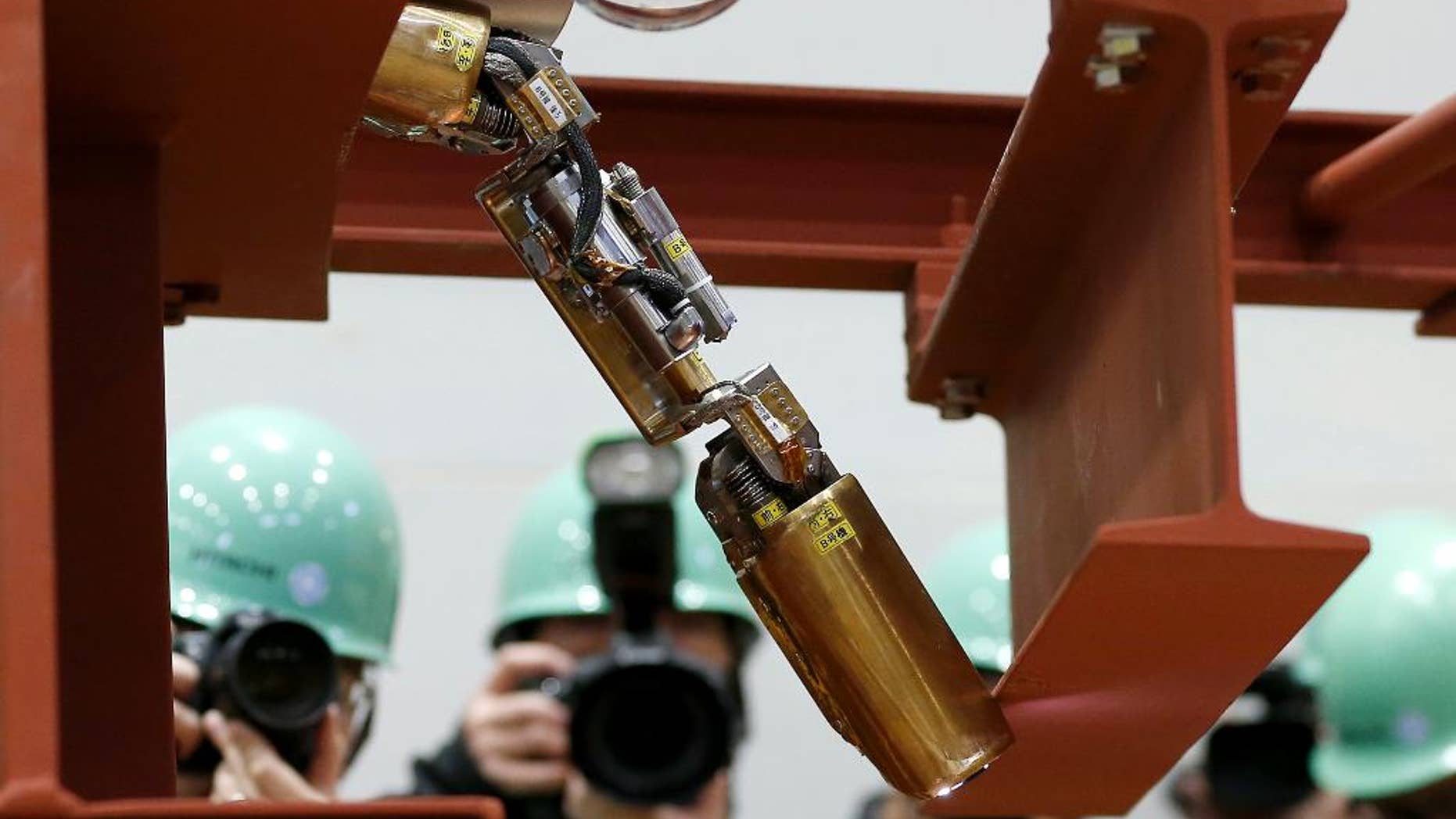 FILE - In this Thursday, Feb. 5, 2015 file photo, a remote-controlled robot that looks like an enlarged fiberscope crawls down into the mock-up of a primary containment chamber of Fukushima Dai-ichi nuclear plant, during a demonstration for the media at a government facility in Hitachi, Ibaraki Prefecture, northeast of Tokyo. Tokyo Electric Power Co., the operator of the wrecked Fukushima nuclear plant, said Monday, April 13, the first robot, the same type shown in the photo, sent inside one of melted reactors stalled before finishing its work but it collected data that indicates a path to send robots deeper into the reactor is intact. TEPCO said the robot stalled after completing two-thirds of Friday's planned mission inside the Unit 1 containment vessel. (AP Photo/Shizuo Kambayashi)