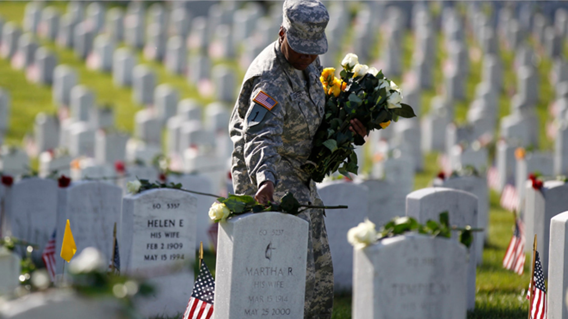 May 27, 2013: A soldier places roses on grave stones in Section 60 of Arlington National Cemetery on Memorial Day in Arlington, Va. Iraq and Afghanistan war veterans are buried in Section 60.