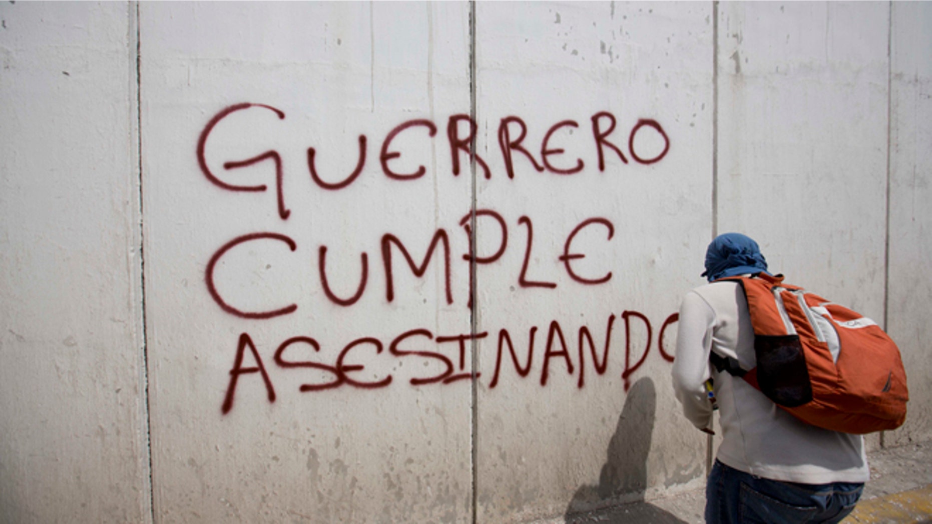 A protester sprays a wall with the words in Spanish "Guerrero follows through with murder" at a demonstration against the disappearance of 43 students from the Isidro Burgos rural teachers college in Chilpancingo, in Guerrero state, Mexico, Wednesday, Oct. 8, 2014. Federal officials say they still have no explanation for violence Sept. 26 that killed six, wounded at least 25 and left so many missing. Also, investigators still had no word on whether the 28 bodies found in a mass grave last weekend included some of the missing students. (AP Photo/Eduardo Verdugo)