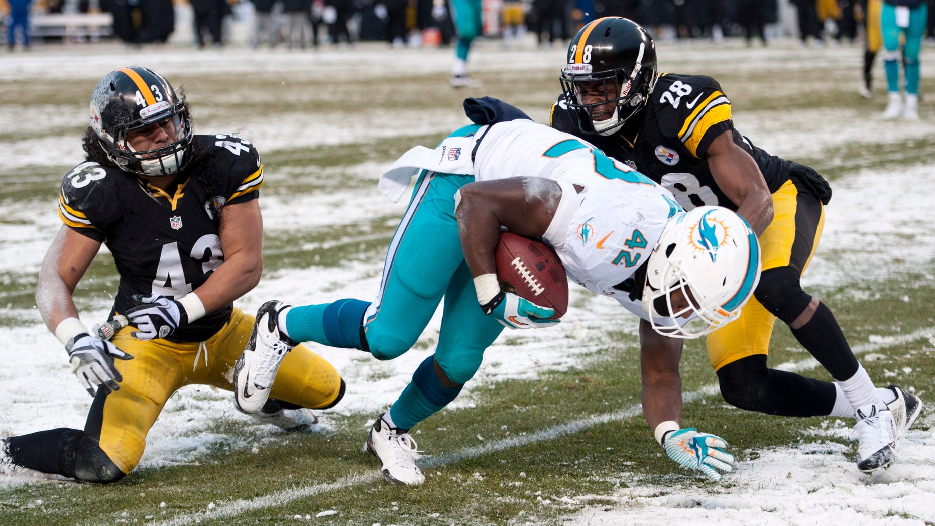 Miami Dolphins tight end Charles Clay (42) slips the tackle of Pittsburgh Steelers strong safety Troy Polamalu (43) and Pittsburgh Steelers cornerback Cortez Allen (28) and heads to the end zone for a touchdown during the second half of an NFL football game in Pittsburgh, Sunday, Dec. 8, 2013. (AP Photo/Don Wright)