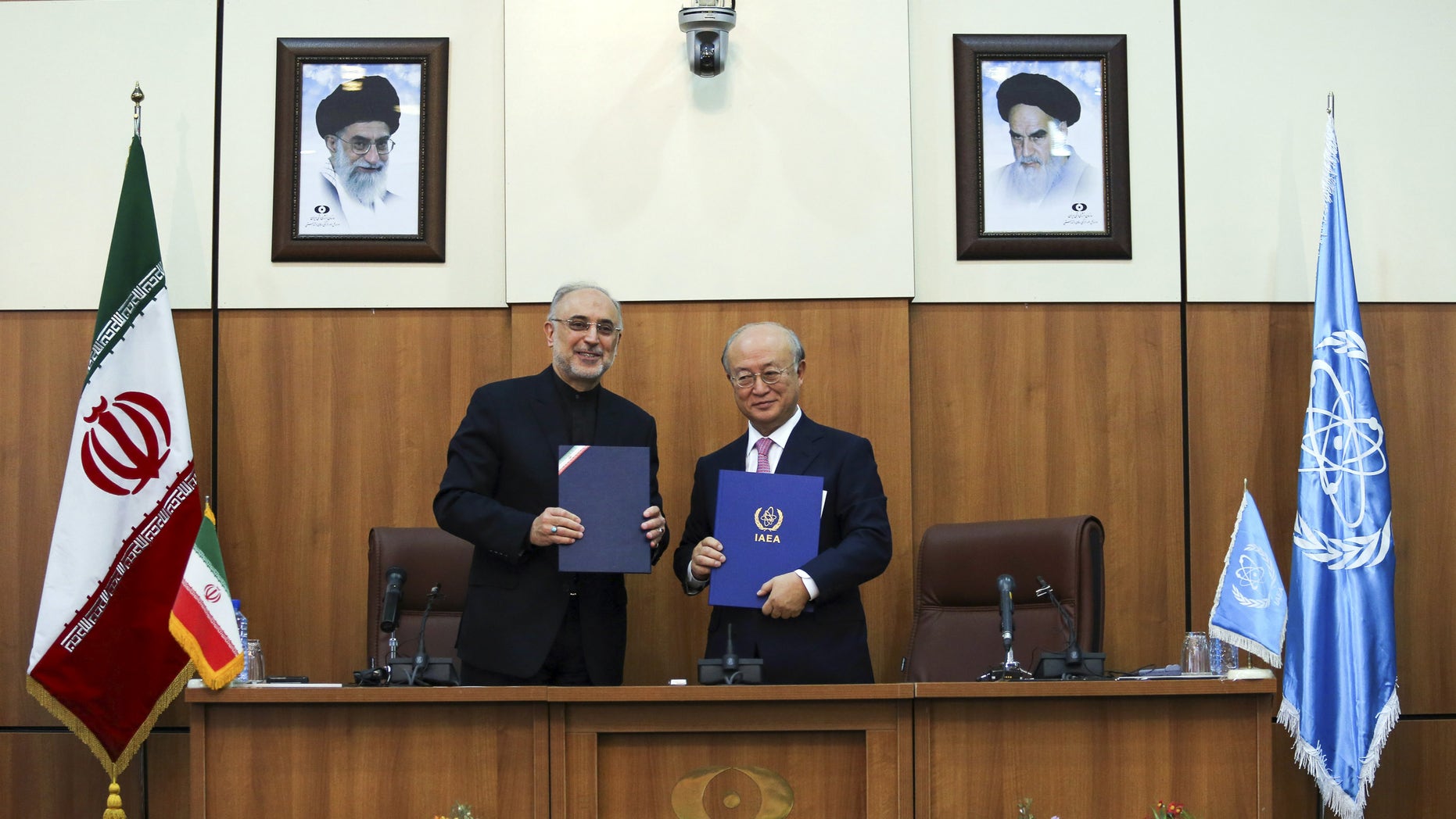 Head of Iran's Atomic Energy Organization Ali Akbar Salehi, left, and International Atomic Energy Agency (IAEA) Director General Yukiya Amano, pose for a photo under portraits of Iran's supreme leader, Ayatollah Ali Khamenei, left, and Iran's founder of Islamic Republic, Ayatollah Ruhollah Khomeini, right, following their meeting in Tehran, Iran, Monday, Nov. 11, 2013. Iran and the U.N. nuclear watchdog agency have reached a roadmap deal for cooperation during talks in Tehran Saturday that expands the monitoring of the country's nuclear sites. (AP Photo/ ISNA, Mehdi Ghasemi)