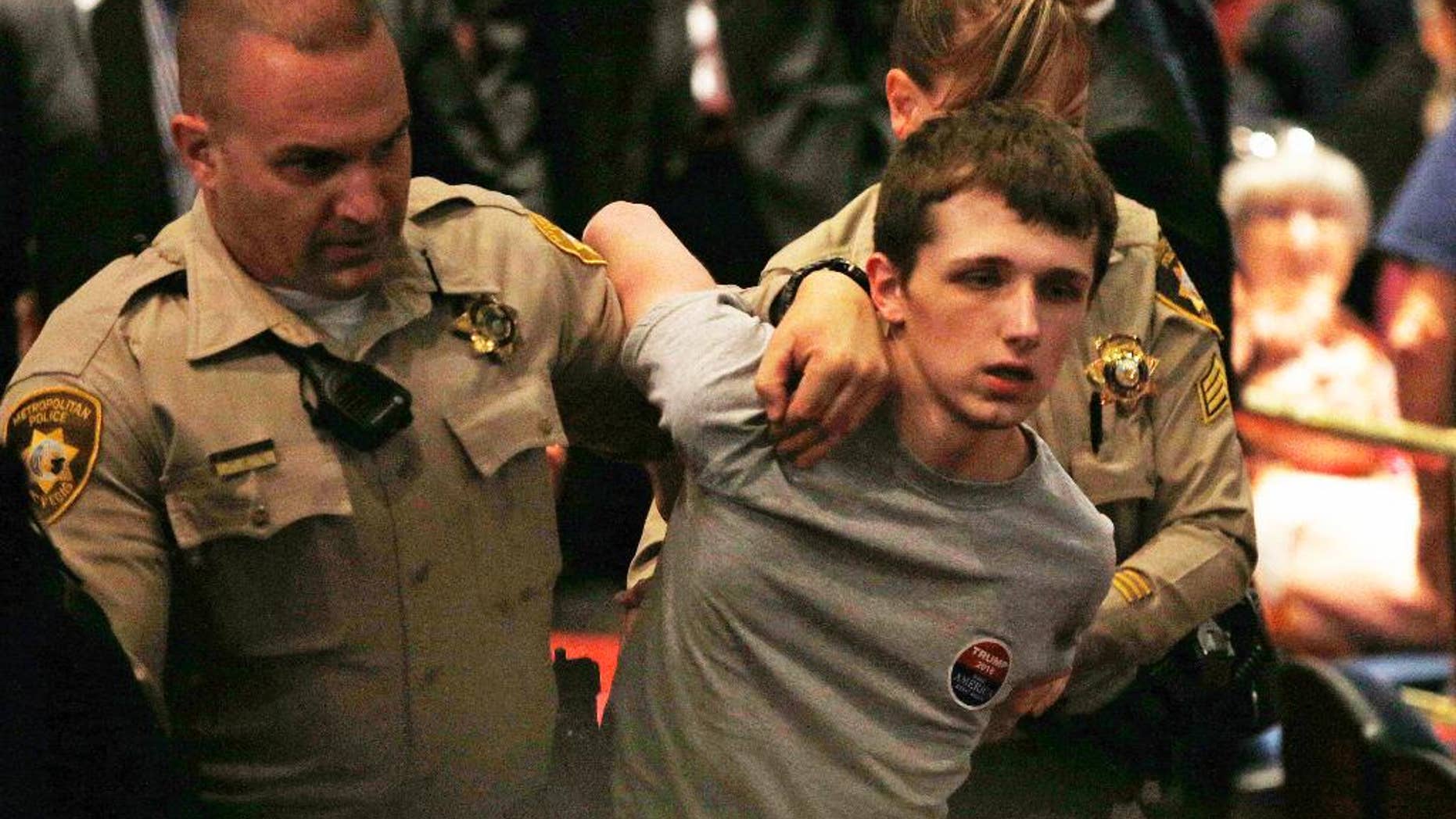 FILE - In this June 18, 2016, photo, police remove Michael Sandford as Republican presidential candidate Donald Trump speaks at the Treasure Island hotel and casino in Las Vegas. The mother of Standford who is accused of attempting to shoot Donald Trump told British television he will plead guilty to lesser charges in a U.S. court. Lynne Sandford, the mother of Michael Sandford, told the station her son has signed a plea agreement in advance of a Nevada court appearance Tuesday, Sept. 13. (AP Photo/John Locher, File)