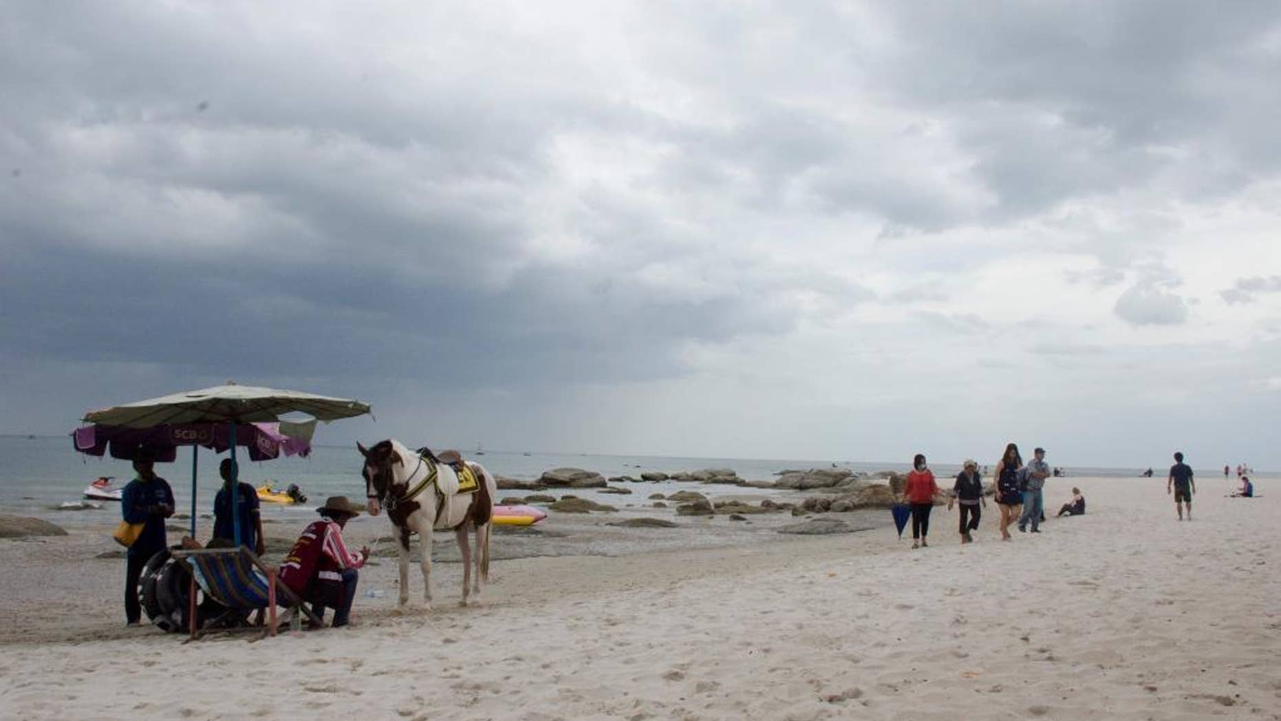 People walk along the beach in Hua Hin, Thailand, Saturday, Aug. 13, 2016. Thais and tourists headed warily into the main part of a big holiday weekend Saturday as police looked for suspects and a motive behind a series of blasts that shook resort towns across Thailand, killing four people and wounding dozens more. (AP Photo/ Penny Yi Wang)