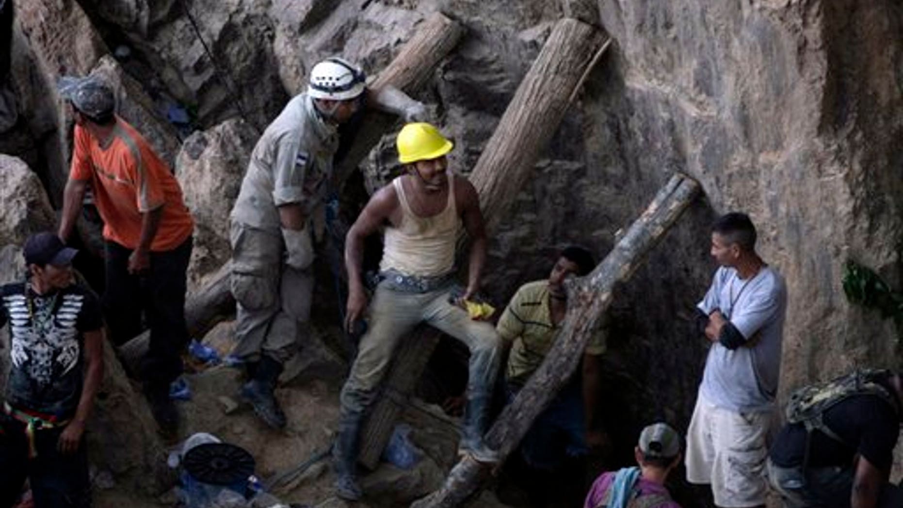 Rescue workers and volunteers stay at a gold mine where 11 miners are trapped inside after a landslide in San Juan Arriba, Choluteca in southern Honduras, Thursday, July 3, 2014. More than 300 Red Cross volunteers, firefighters and people who live near the mine in the town of El Corpus were digging by hand in an effort to reach the miners. (AP Photo/Fernando Antonio)