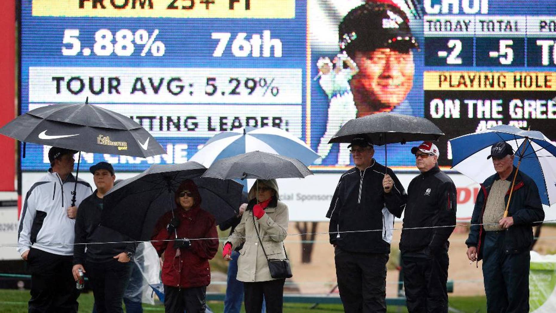 Fans, holding umbrellas, line up in front of the ninth hole during the second round of the Phoenix Open golf tournament, Friday, Jan. 30, 2015, in Scottsdale, Ariz. (AP Photo/Rick Scuteri)