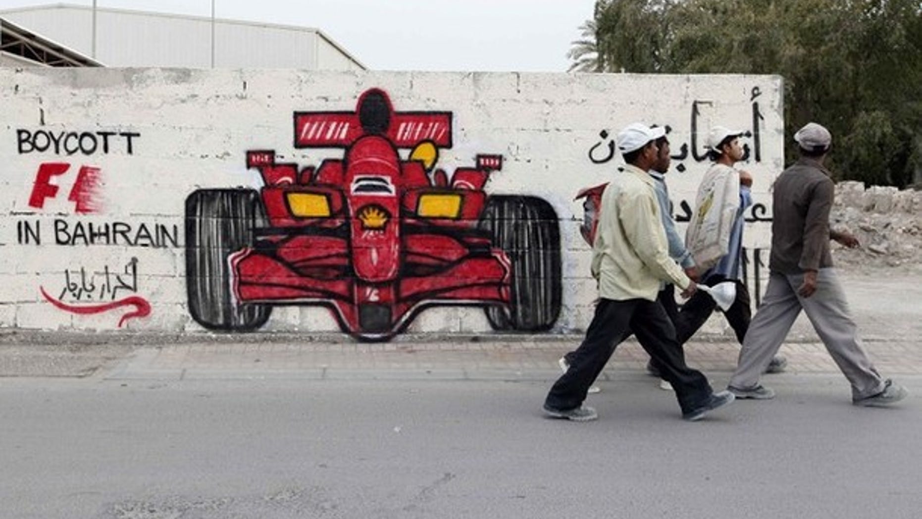 Men walk past anti-Formula One graffiti in the village of Barbar, west of Manama April 5, 2012. Former world champion Damon Hill has called on Formula 1 bosses to reconsider going ahead with this month's controversial Bahrain Grand Prix and warned that the sport's image could suffer if the race is held.