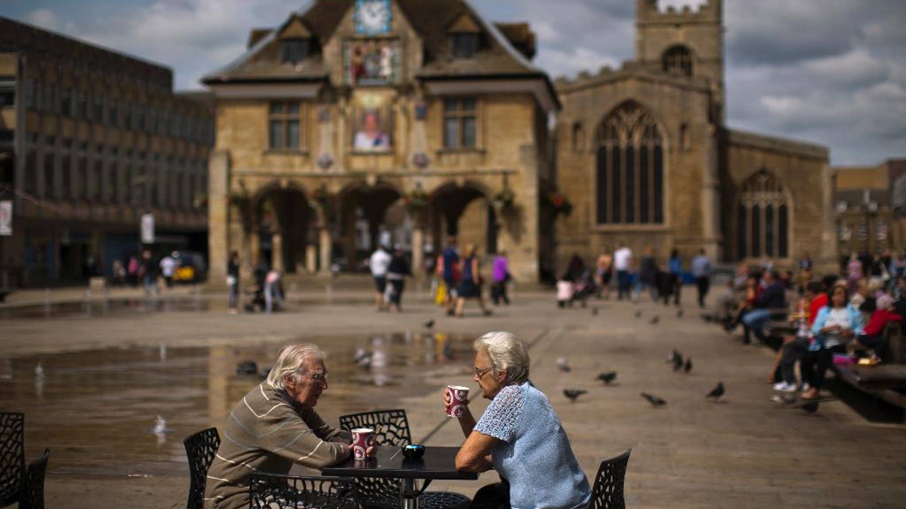 In this Wednesday, July 6, 2016 photo, a couple drink coffee in front of the Guildhall, also known as the Butter Cross, on Cathedral Square, in downtown Peterborough, East of England. Many people who voted for Britain to get out of the European Union look at multi-ethnic Peterborough as a warning example. They say British identity has been eroded in parts of the city where migrants have moved in and pubs have been replaced by shawarma shops or ethnic food stores. (AP Photo/Emilio Morenatti)