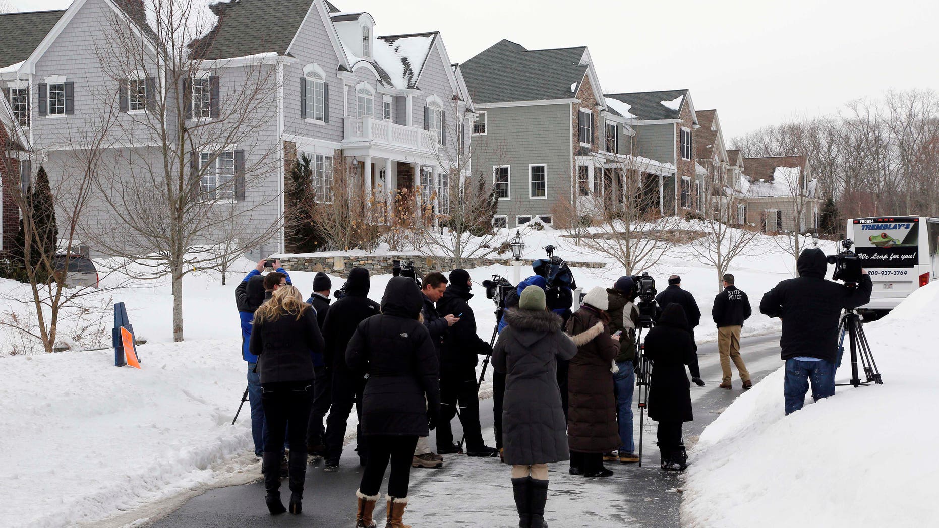 Media members and police officers stand near a bus sitting in front of the North Attleborough, Mass., home of former New England Patriots football player Aaron Hernandez, rear, during a site visit by the jury in his murder trial Friday, Feb. 6, 2015. Hernandez is charged with killing semiprofessional football player Odin Lloyd in 2013. The jury was bused to several sites related to the case, including Hernandez's home, Lloyd's home, and the industrial park where Lloyd's body was found. (AP Photo/Steven Senne, Pool)