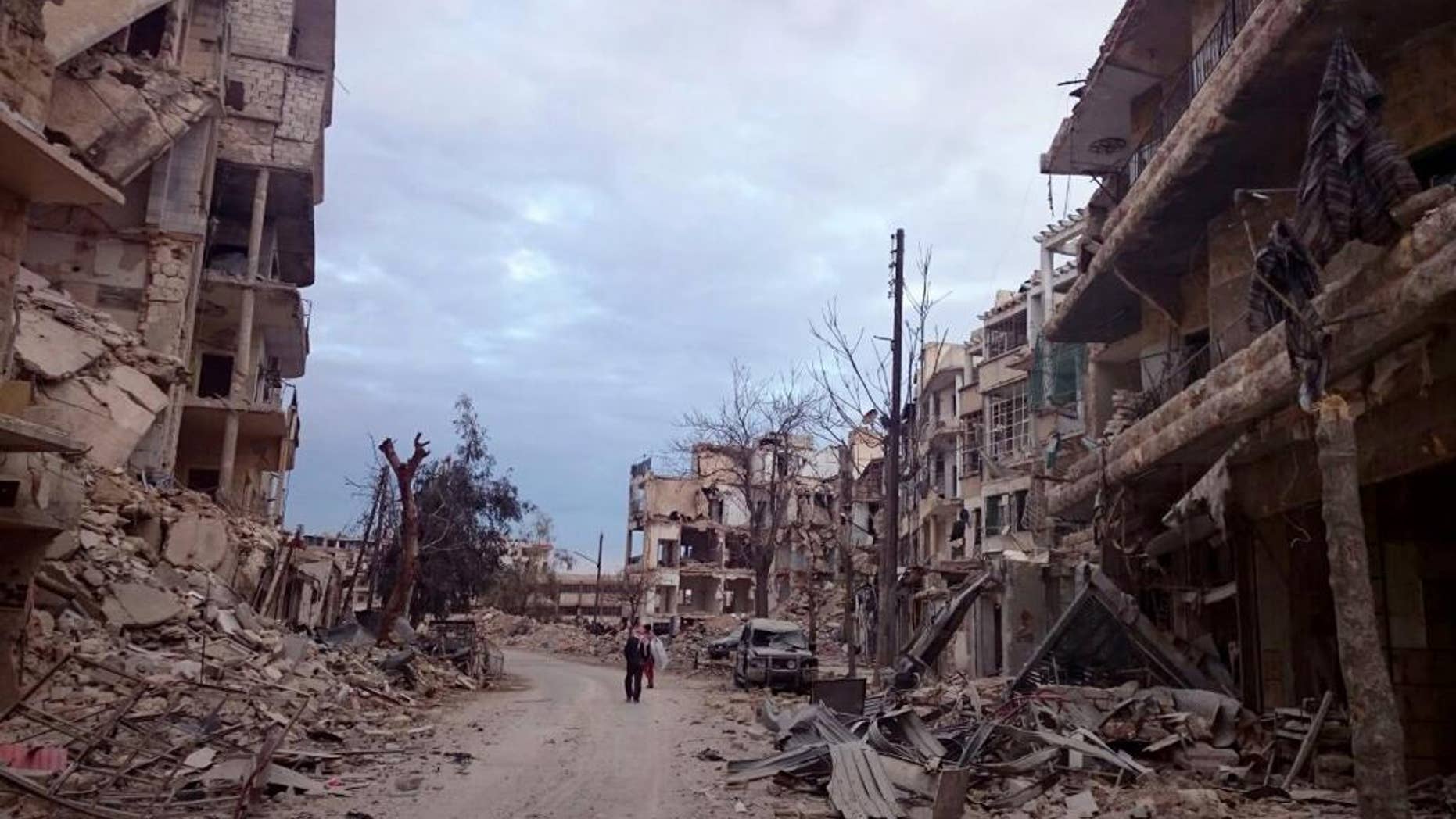 In this photo, courtesy of Wissam Zarqa, a Syrian English teacher and vocal anti-government critic, men walk past damaged buildings and shops in the eastern Aleppo neighborhood of al-Mashhad, Syria, Thursday, Dec. 8, 2016. Government troops and allied militiamen have been advancing swiftly into the once rebel-controlled eastern Aleppo enclave as defenses of the opposition fighters buckle. (Courtesy of Wissam Zarqa, via AP)
