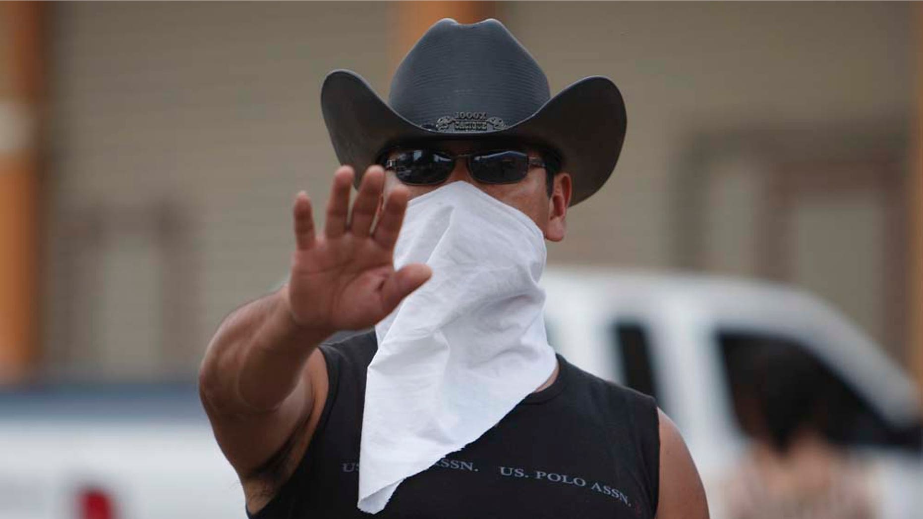 In this photo taken Saturday May 14, 2011, a masked man gestures to the camera as he stands guard at a barricade in Cheran, Michoacan State, Mexico. The men of Cheran started taking security into their own hands last month by setting up checkpoints at the entrance of town with tires and sandbags and using guns they stole from local police after loggers, who residents say are backed by cartel henchmen and local police, killed two residents and wounded several others. (AP Photo/Miguel Tovar)