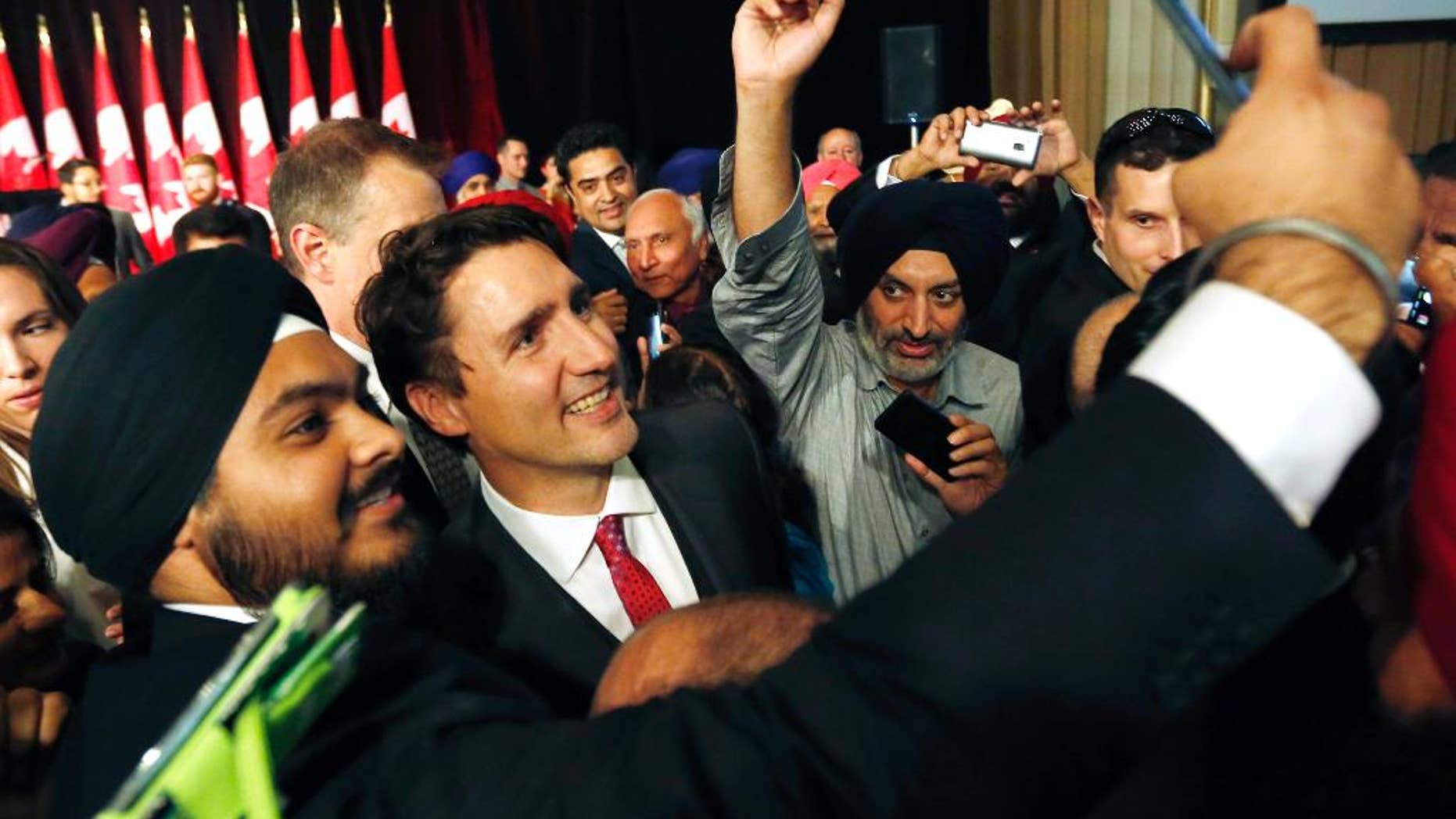 Prime Minister Justin Trudeau, center, smiles as a person takes a selfie photograph with him after he delivered remarks at the Komagata Maru Apology reception in Ottawa, on Wednesday, May 18, 2016. A New Democrat MP says Prime Minister Justin Trudeau "manhandled" another member on the floor of the House of Commons just prior to a key vote. (Fred Chartrand/The Canadian Press via AP) MANDATORY CREDIT