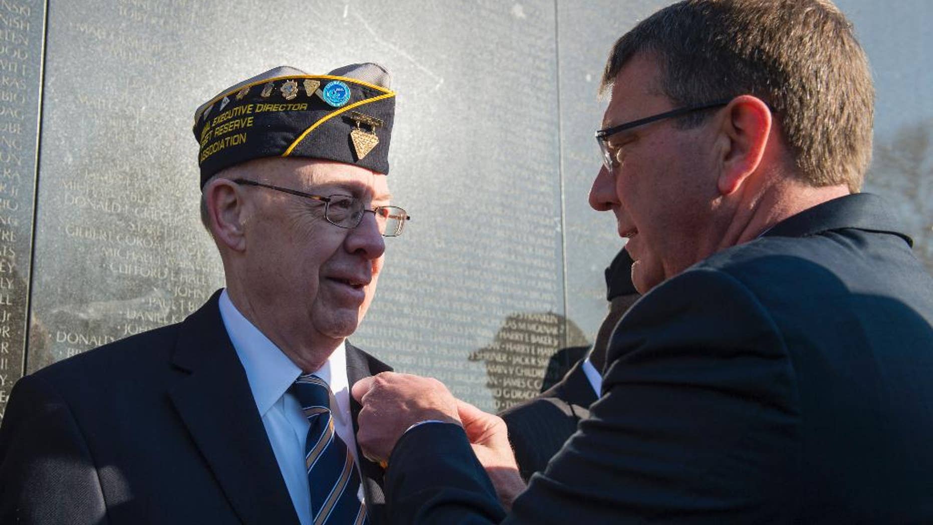 Defense Secretary Ash Carter honors Vietnam Veteran Thomas Snee, who served in the Navy, with a commemorative pin to mark the 50th anniversary of the Vietnam War at the Vietnam Memorial Wall in Washington, Tuesday, March 29, 2016. (AP Photo/Molly Riley)