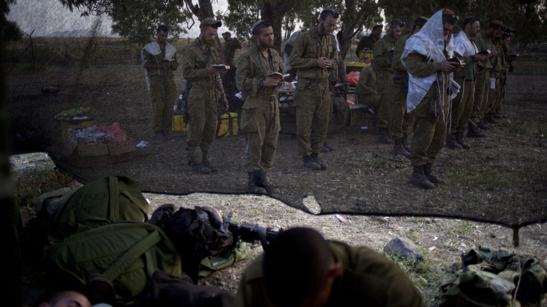 Israeli soldiers of the Golani brigade, few covered in a prayer shawls gather for the morning prayer before a military exercise in the Israeli controlled Golan Heights, near the border with Syria, Tuesday, May 7, 2013. (AP Photo/Ariel Schalit)